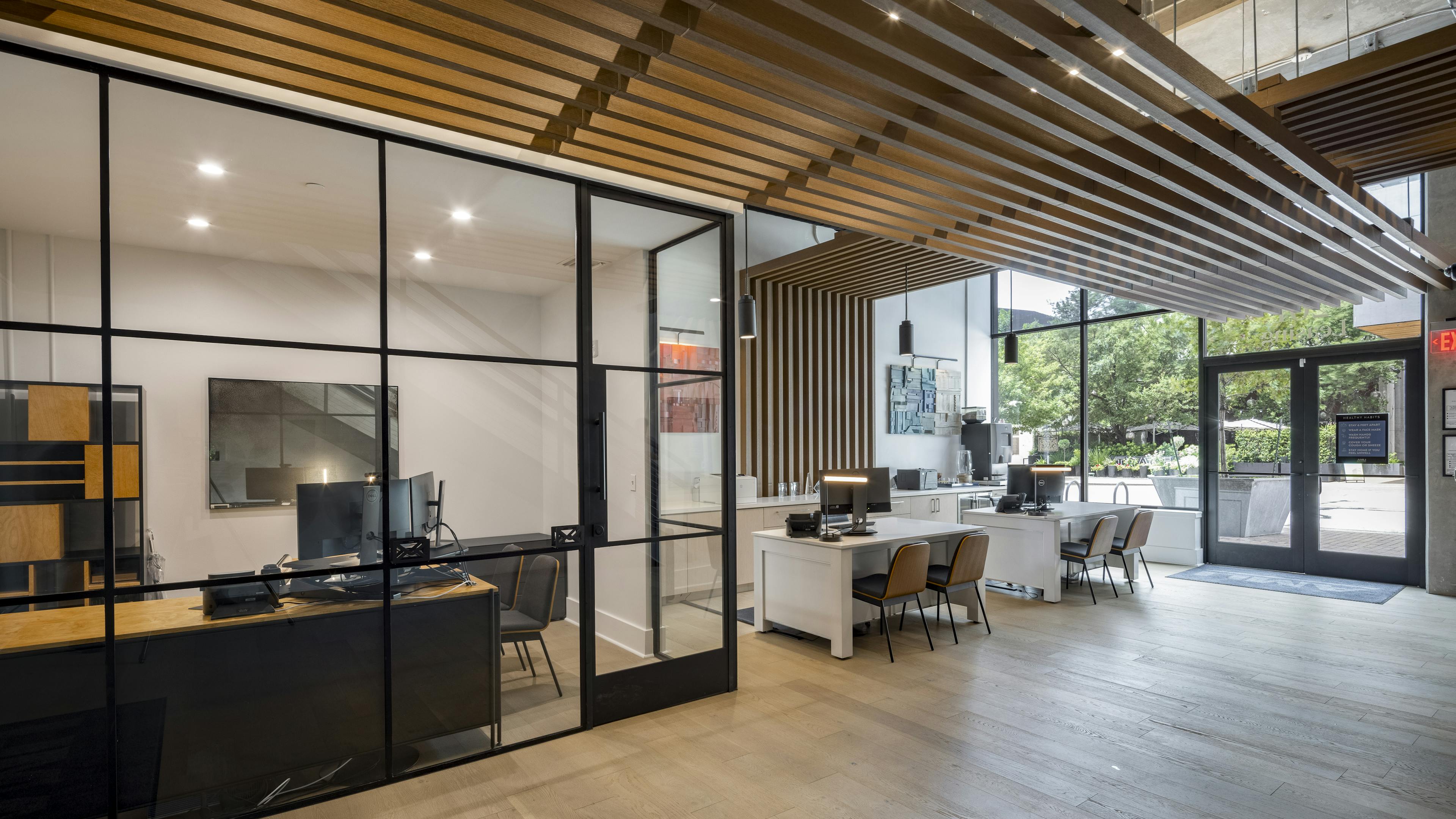 Leasing office at AMLI Downtown apartments with large street facing windows and two leasing desks with wooden chairs 