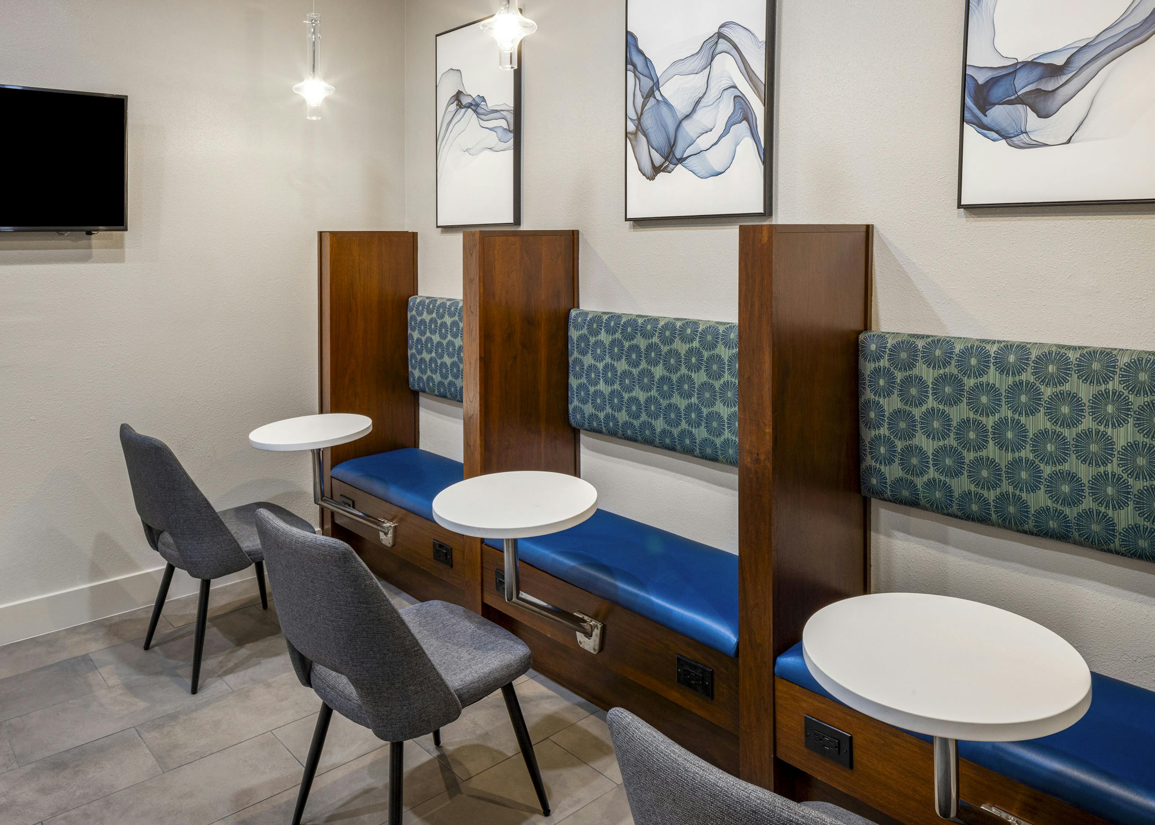 Co-working space at AMLI on Aldrich with 3 wood and blue cushion booths with circular white tables with gray chairs