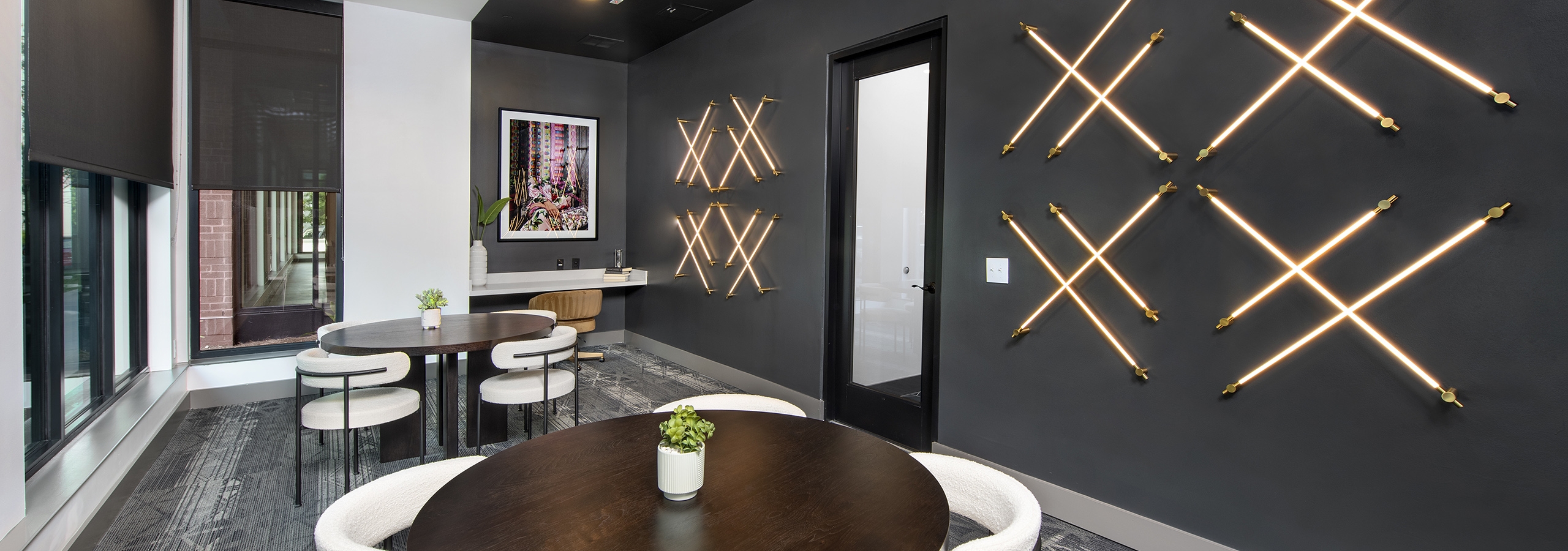 Conference room at AMLI Flatiron with dark grey walls and LED lights in a crisscross pattern with wood tables and white chairs