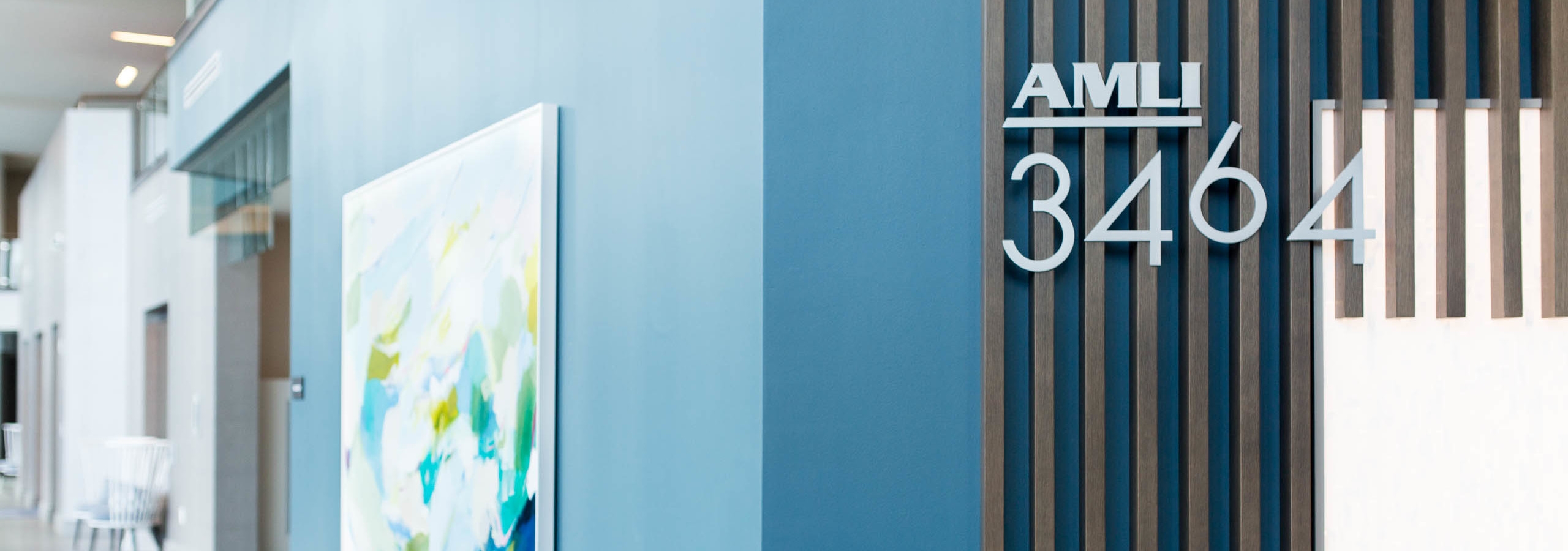 Interior view of the lobby at AMLI 3464 apartment community with light blue walls and an abstract art wall hanging