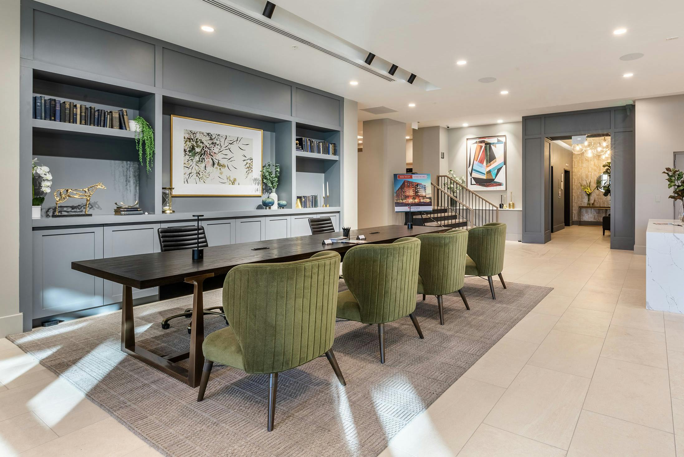 AMLI at Uptown amenity lobby with grey built in shelving and light tile flooring with a sleek wooden conference table
