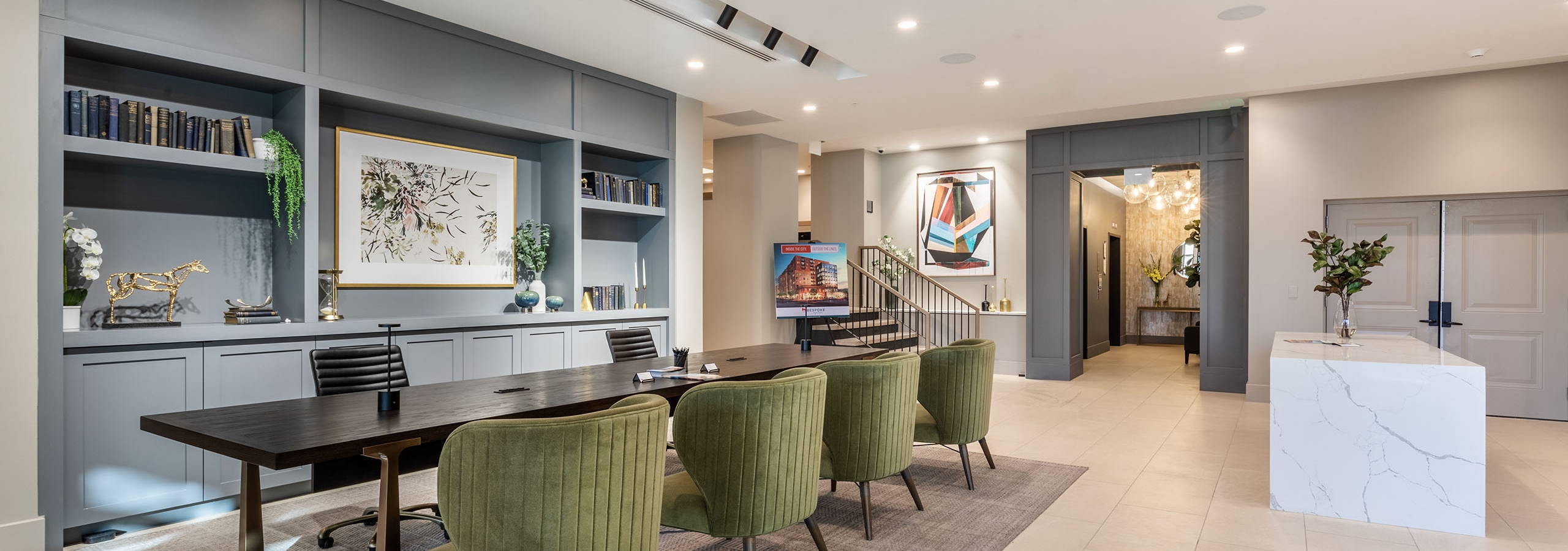 AMLI at Uptown amenity lobby with grey built in shelving and light tile flooring with a sleek wooden conference table