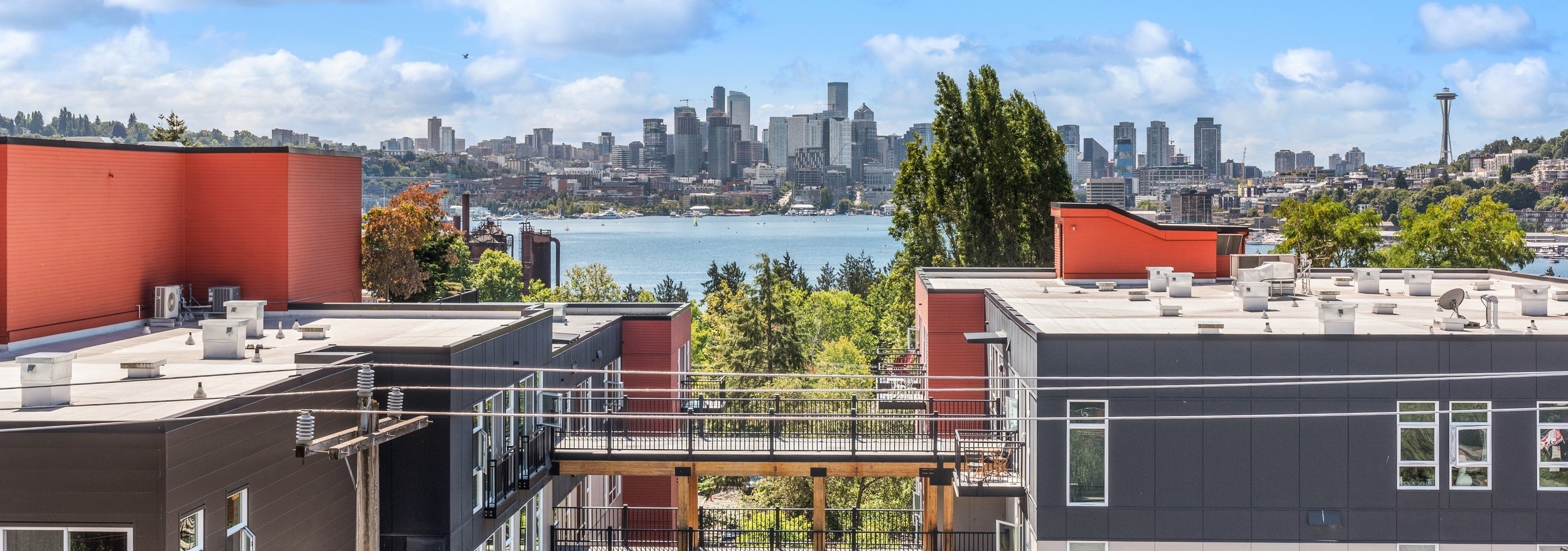 Exterior view from AMLI Wallingford with building rooftops and green trees and Lake Union and the Seattle skyline
