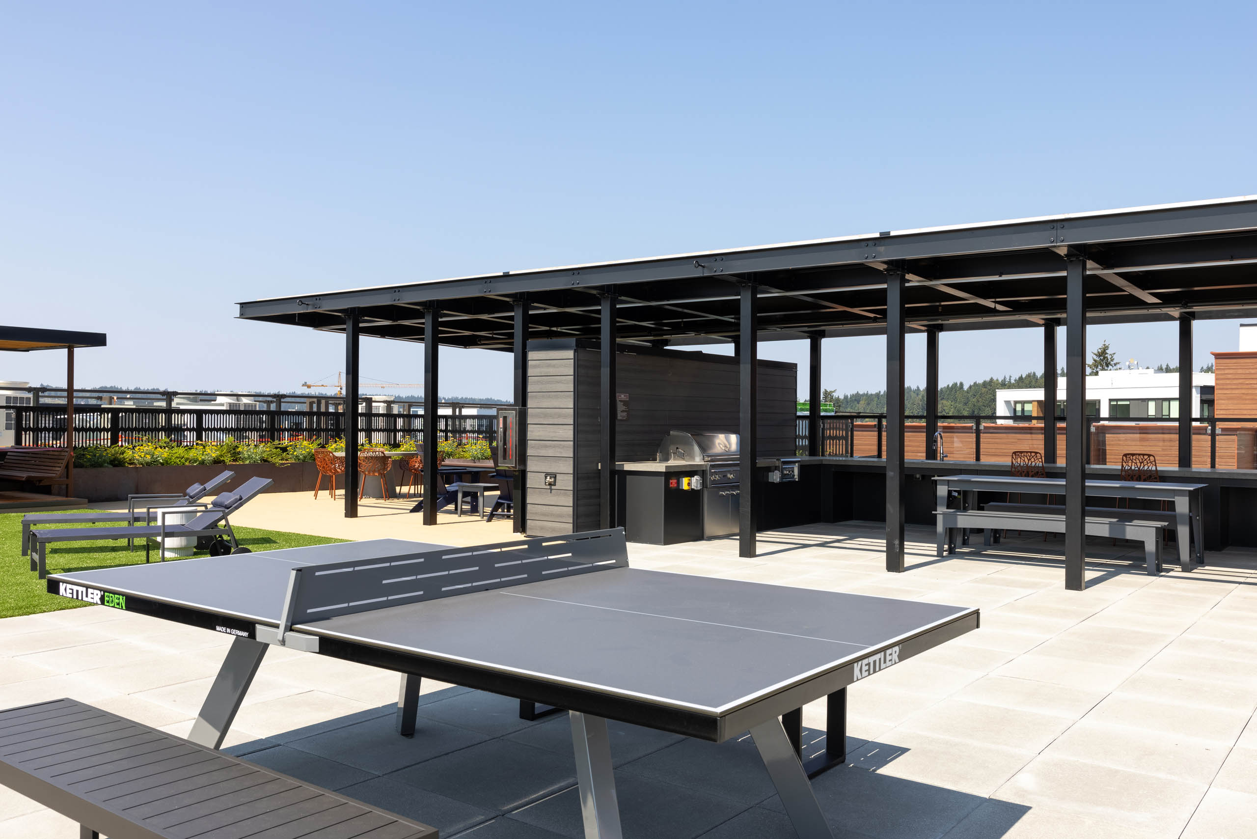 Perch rooftop deck with an outdoor ping pong table, covered grilling and dining stations, lounge chairs, and views of the surrounding neighborhood.