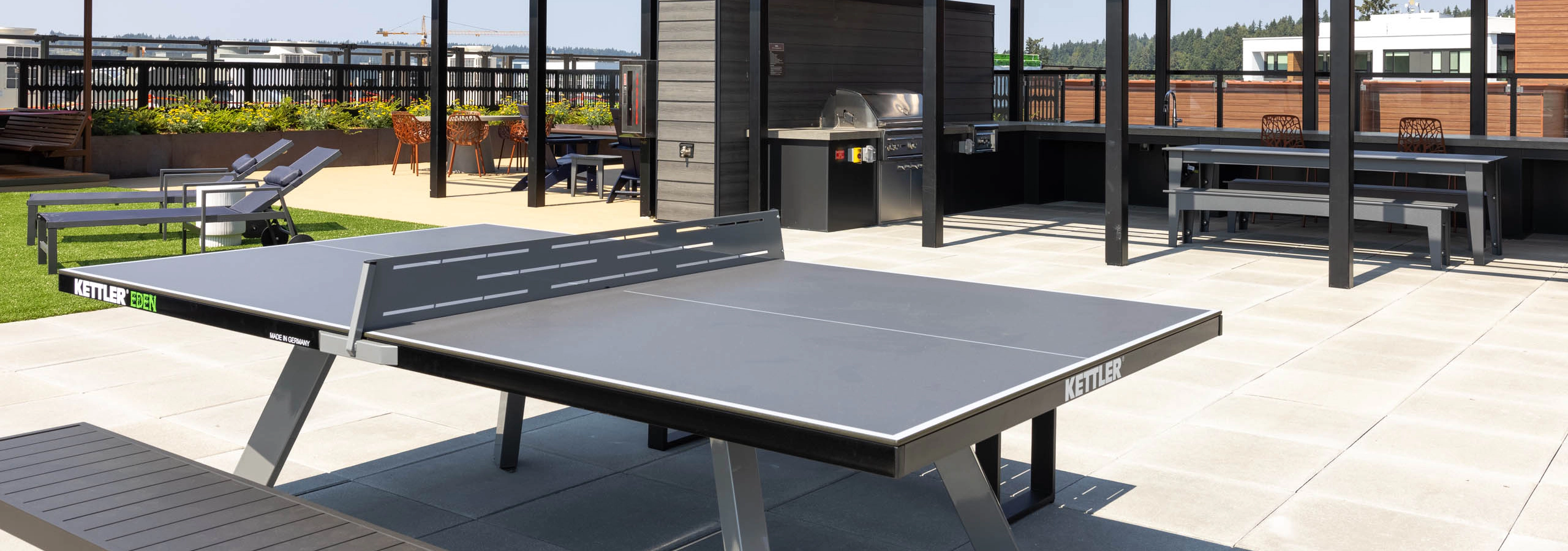 Perch rooftop deck with an outdoor ping pong table, covered grilling and dining stations, lounge chairs, and views of the surrounding neighborhood.