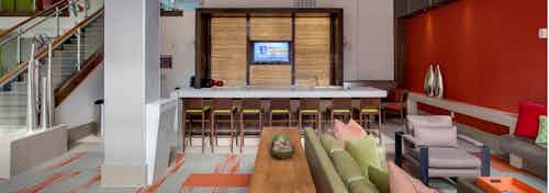 AMLI Ponce Park clubroom with large countertop for entertaining and multiple areas of seating with staircase to upstairs area