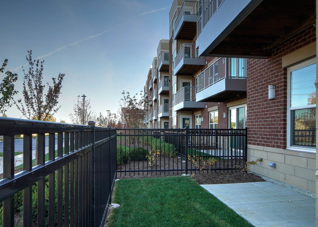Exterior view of first floor private fenced in patio and lawn in the daytime light at AMLI Deerfield apartment community