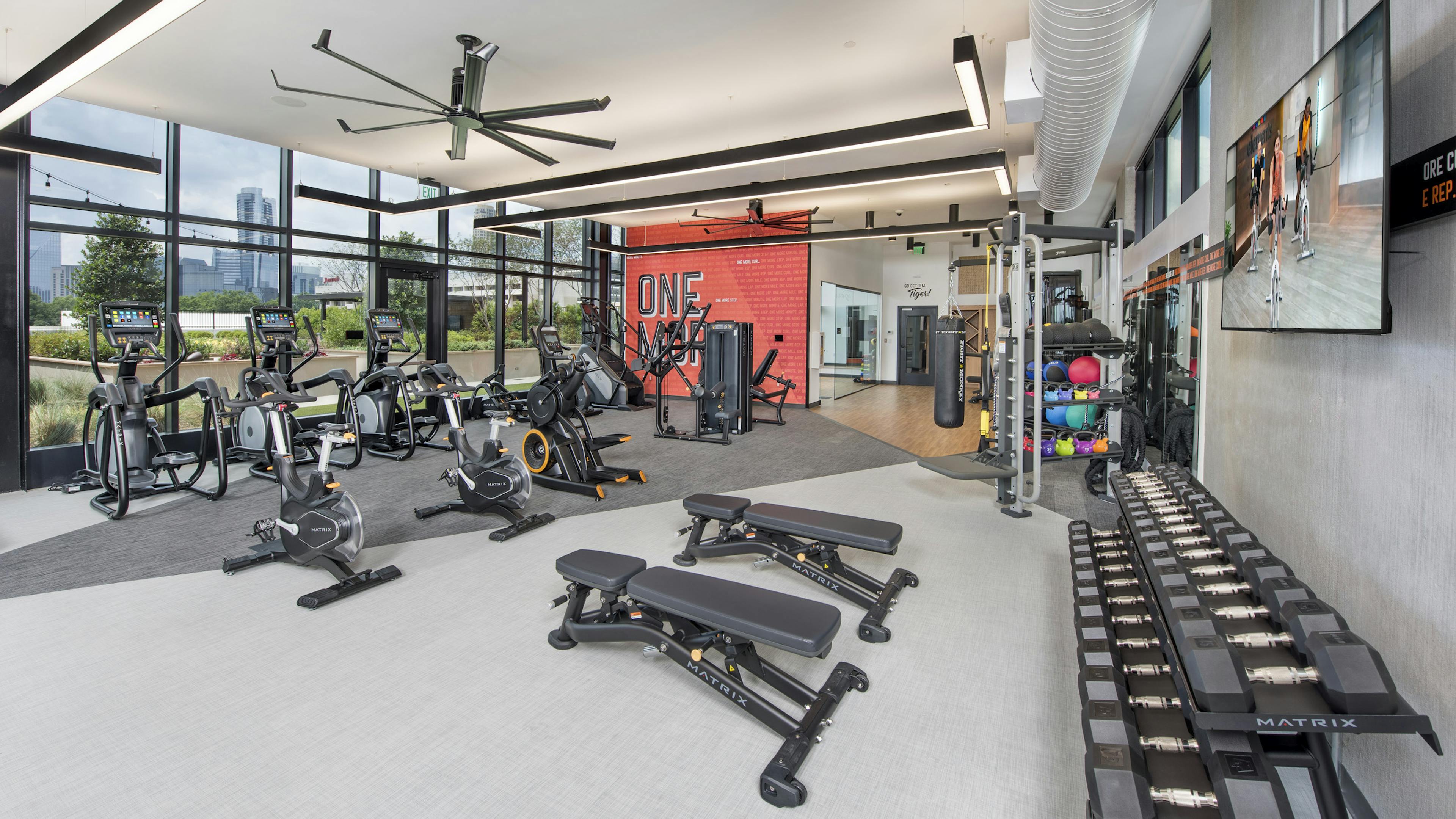 Interior view of AMLI Lenox fitness center with ellipticals and spin bikes and benches and free weights and punching bag 