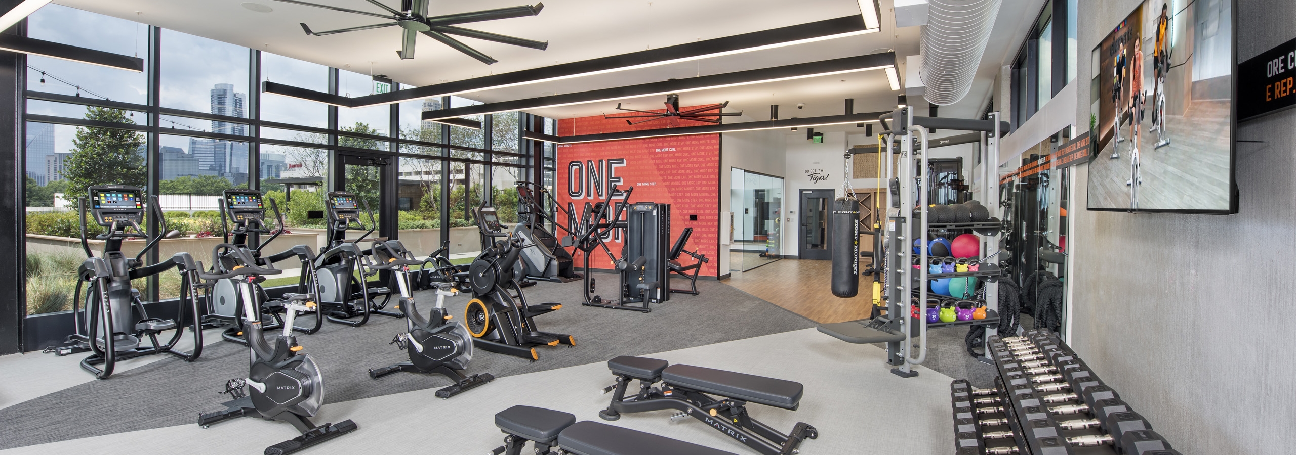 Interior view of AMLI Lenox fitness center with ellipticals and spin bikes and benches and free weights and punching bag