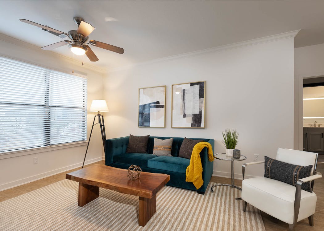 View of living room at AMLI Quadrangle with neutral walls with blue velvet couch and wooden coffee table