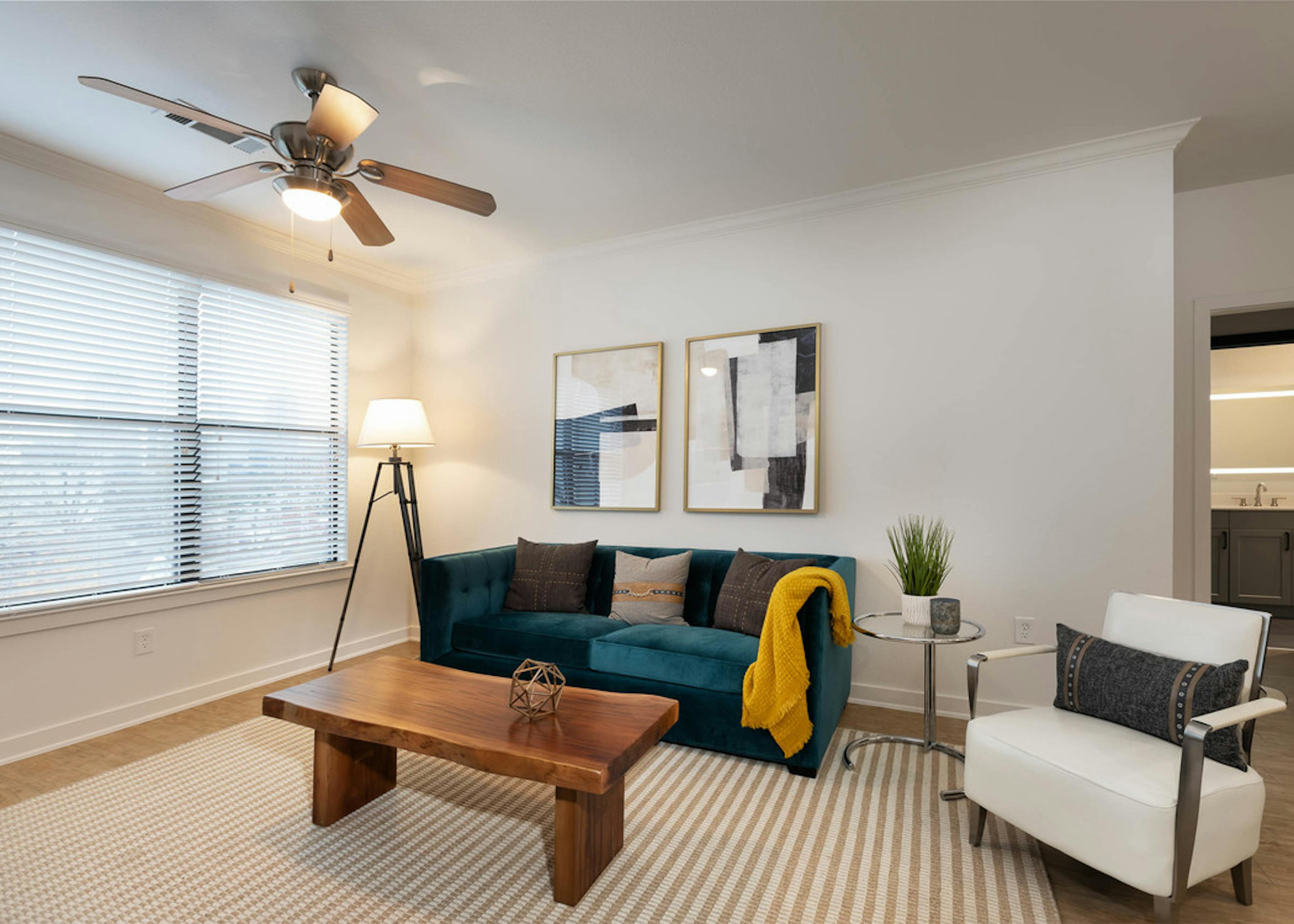 View of living room at AMLI Quadrangle with neutral walls with blue velvet couch and wooden coffee table