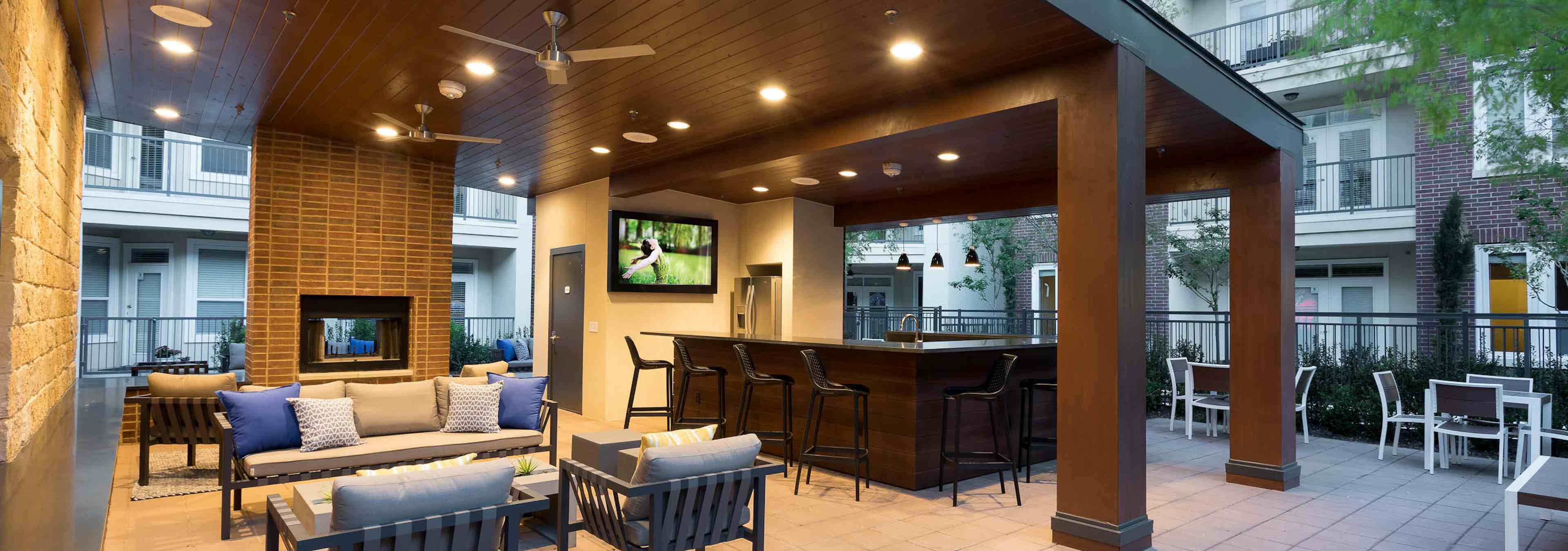 Nighttime view of cabana at AMLI Frisco Crossing apartments with serving bar with chairs, big screen TV and seating areas