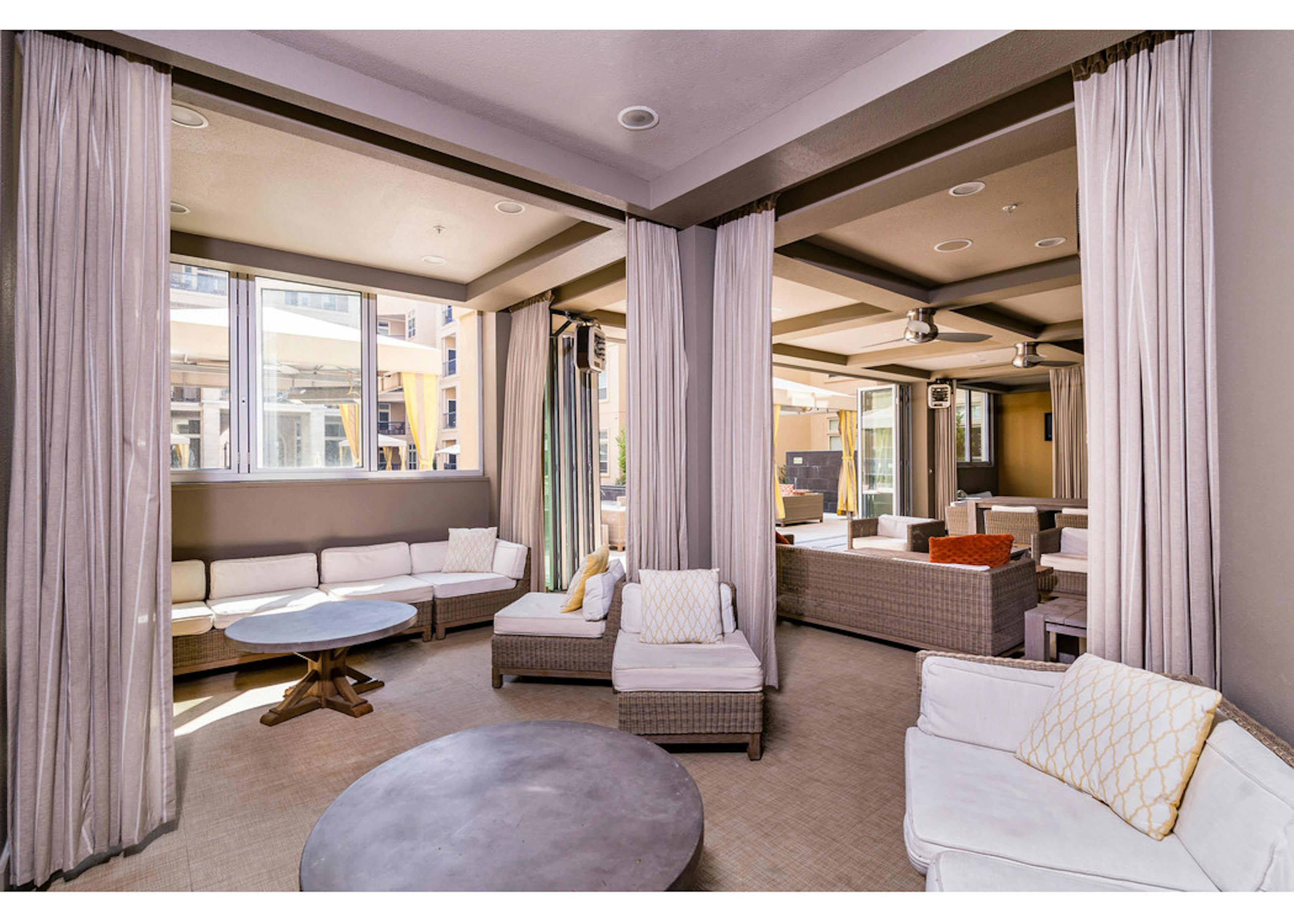 Daytime interior of poolside clubhouse with stylish lounge seating and room divider curtains at AMLI RidgeGate apartments