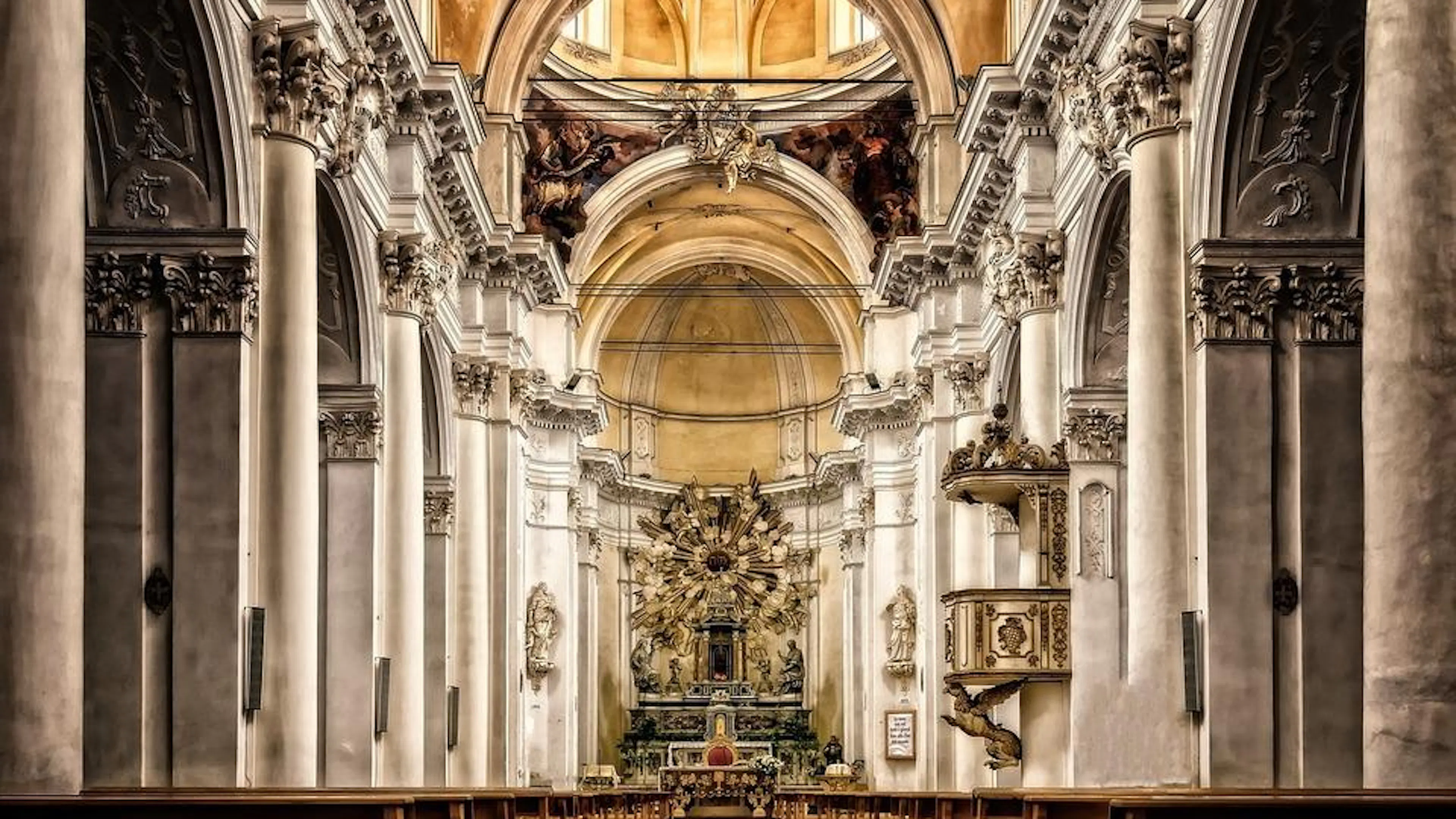 The interior of a large cathedral with tall marble pillars and an elaborate altar