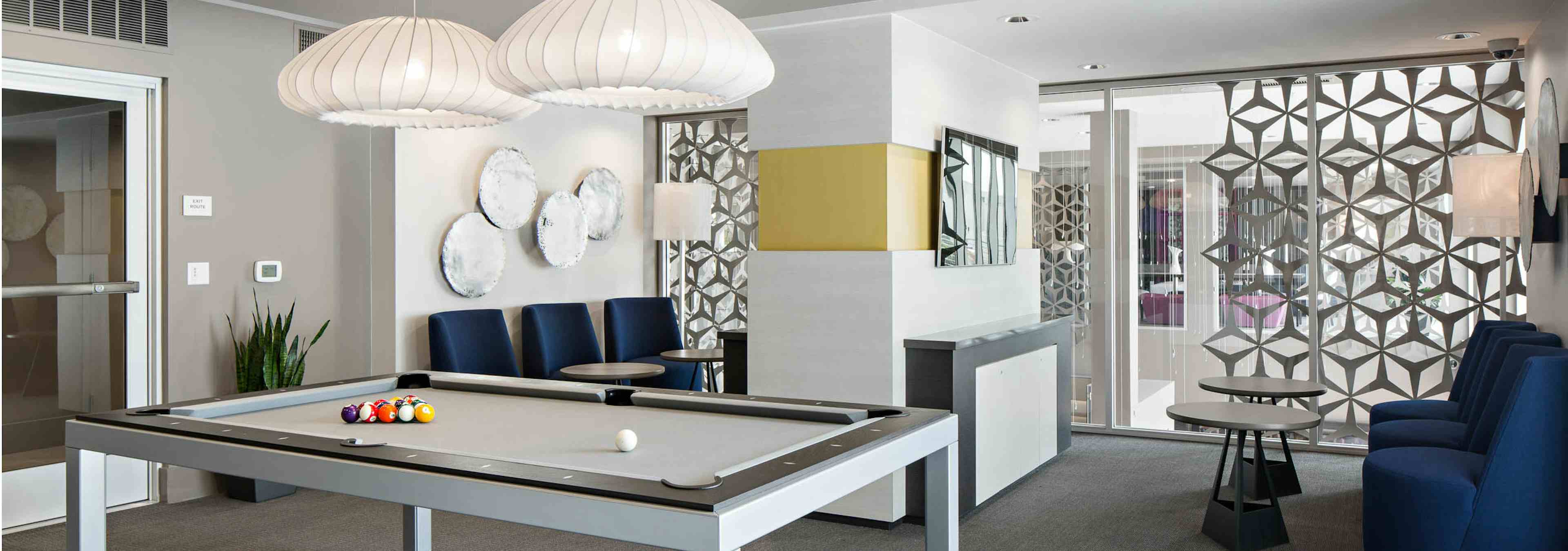 Interior view of gaming lounge at AMLI Lex on Orange apartments with white coral-shaped lighting above pool table and seating