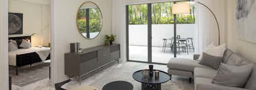 Interior view of AMLI Midtown Miami living room with sofa and two chairs and view of patio and peek into the bedroom