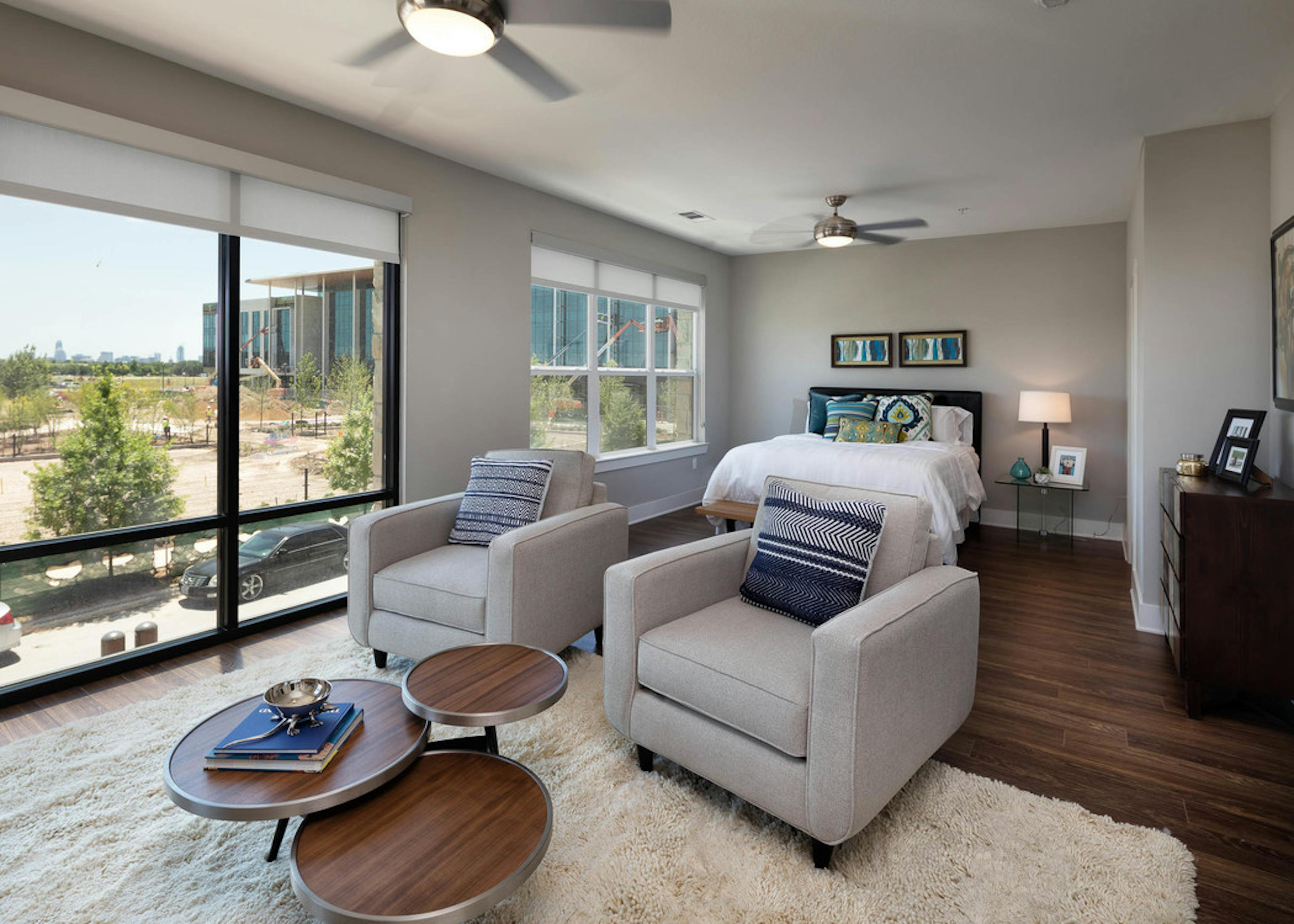 AMLI on Aldrich living room with two white chairs near floor to ceiling windows with dark wood floors and neutral walls