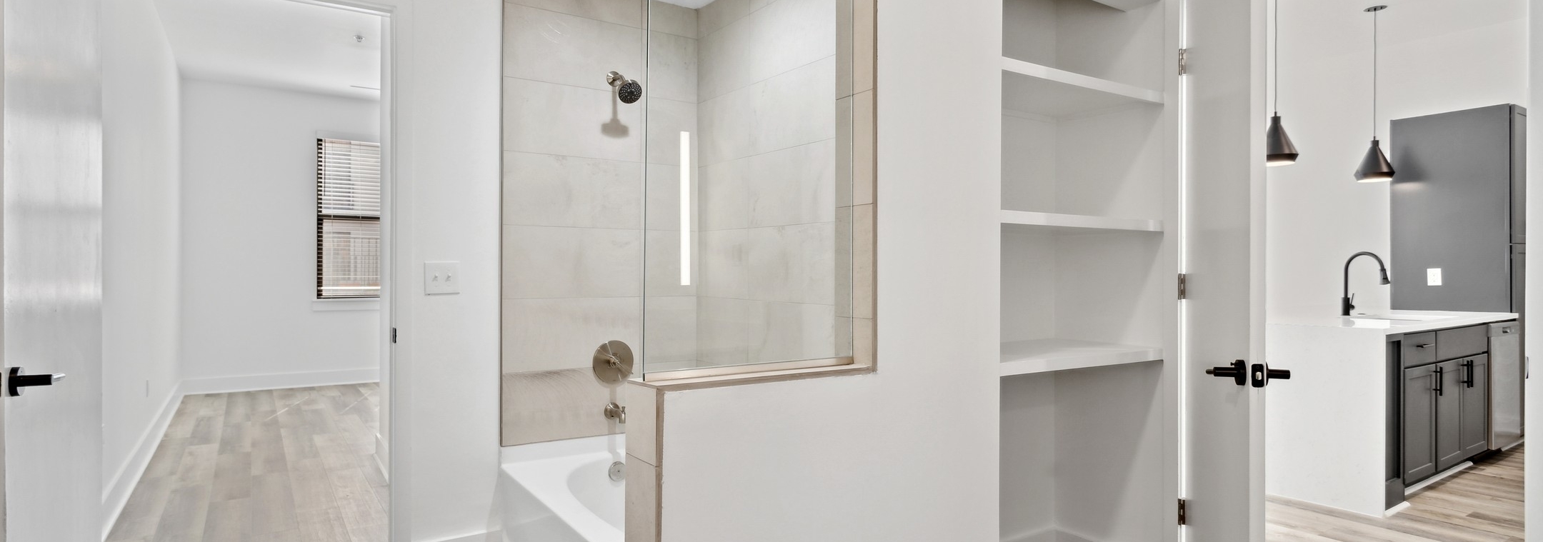 AMLI Old 4th Ward bathroom with a cream tiled shower/tub surround and shelved storage nook with view to bedroom and kitchen