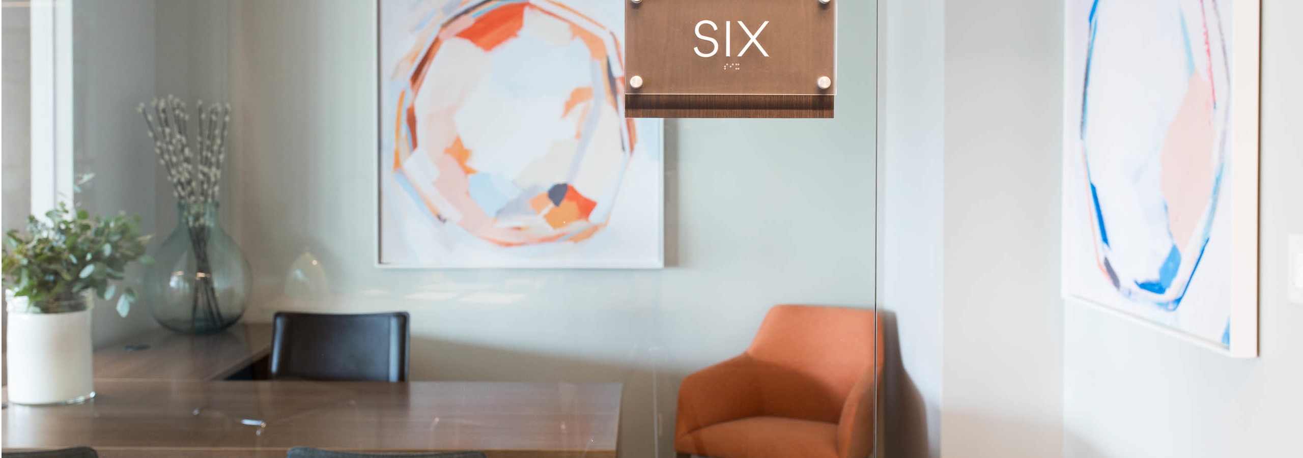 AMLI 3464 private office with a wood desk and an orange office chair in the corner matching a large hanging wall art piece