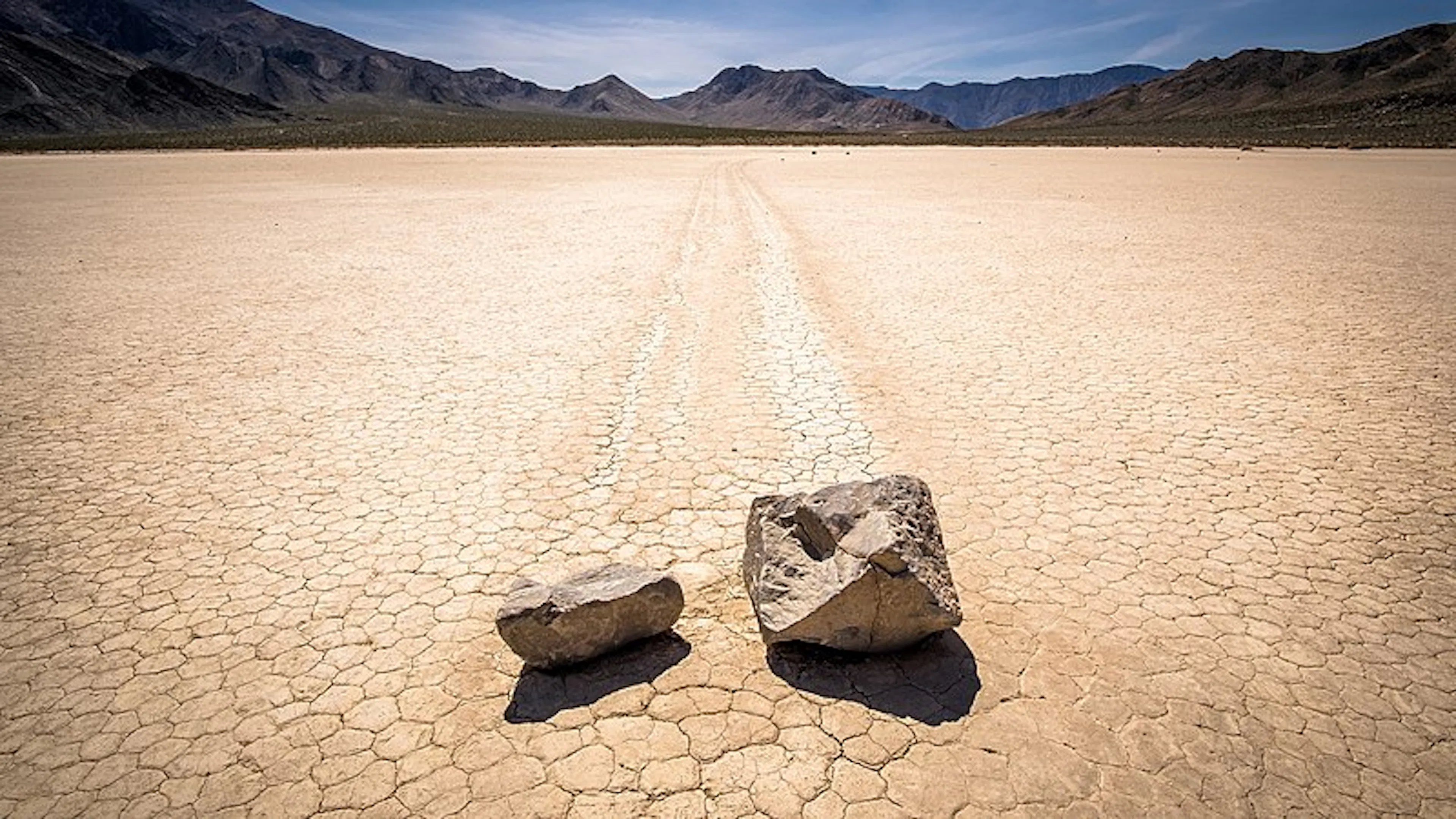 Two rocks with trails in the middle of a large dry lake in Death Valley
