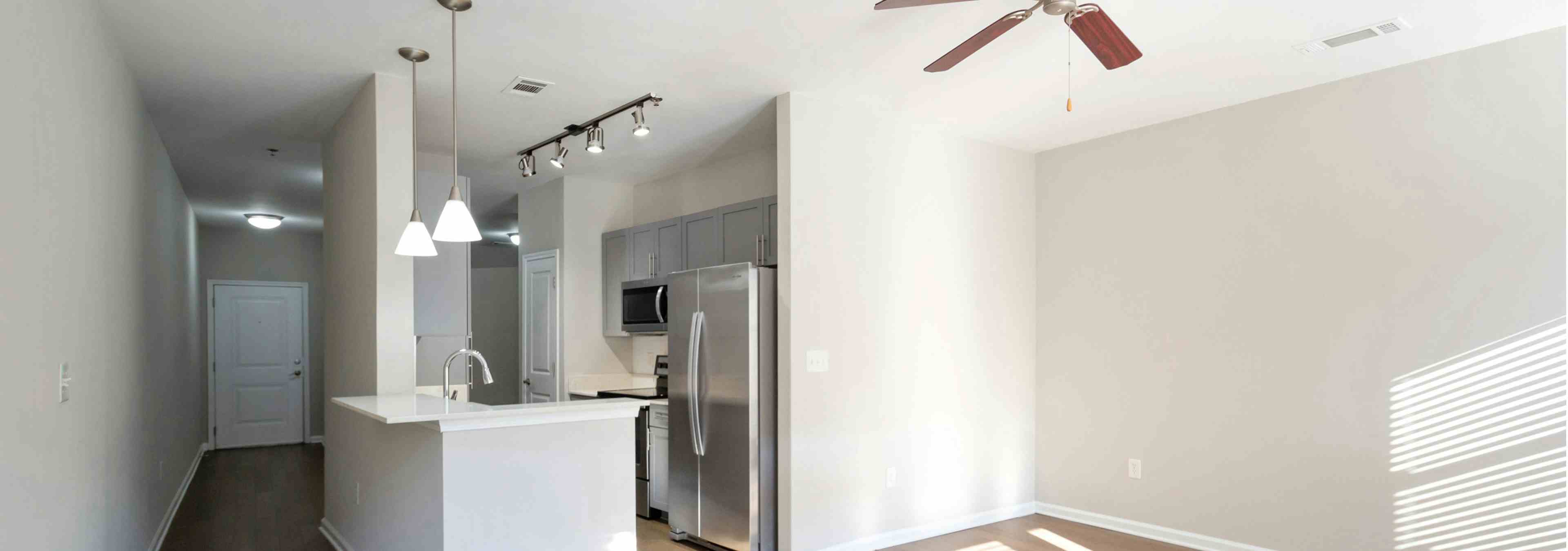 Interior view of AMLI Lindbergh kitchen with stainless steel appliances and light wood flooring which leads into living room