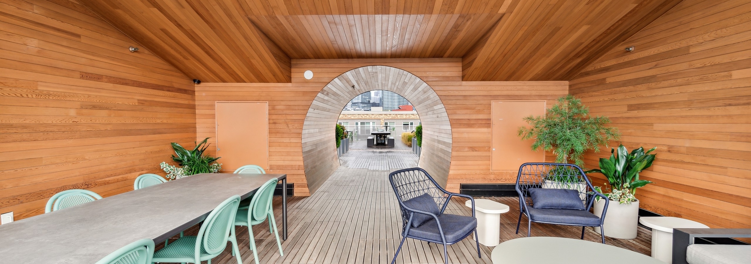Sky deck at AMLI South Lake Union with tables and chairs as well as potted plants and a view of a wood tunnel to larger deck