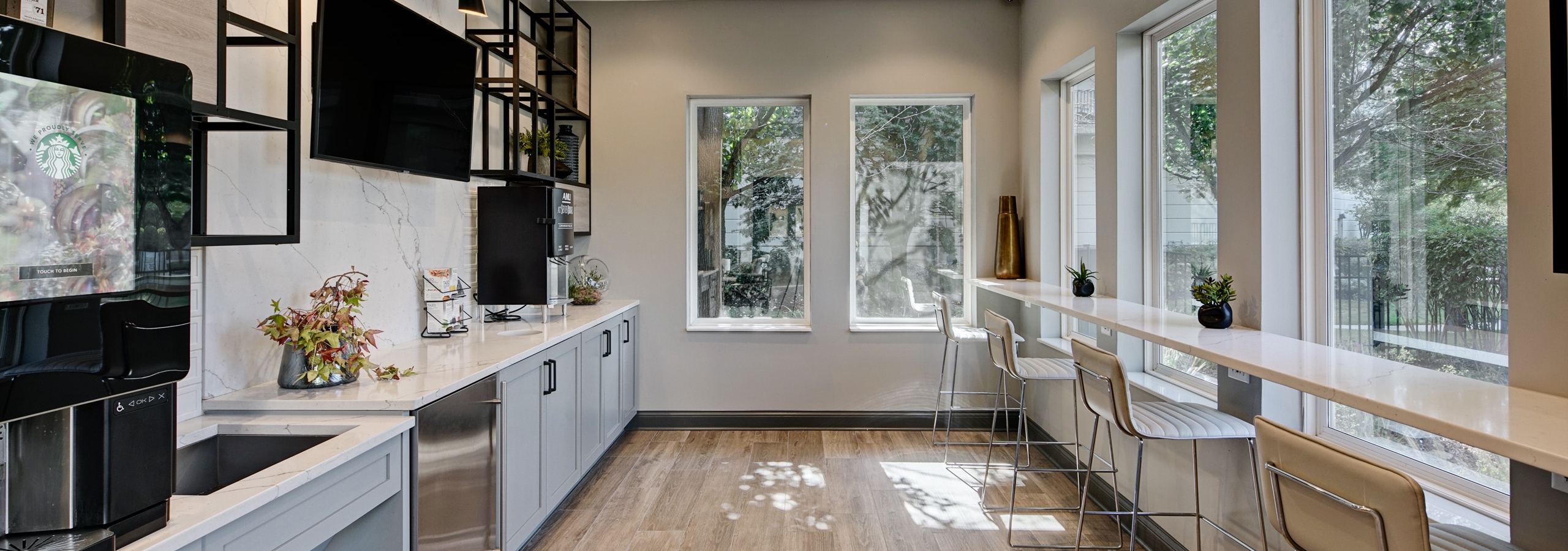 Coffee bar and kitchen area at AMLI at Seven Bridges with Starbucks coffee machine and wall of windows with counter and stools