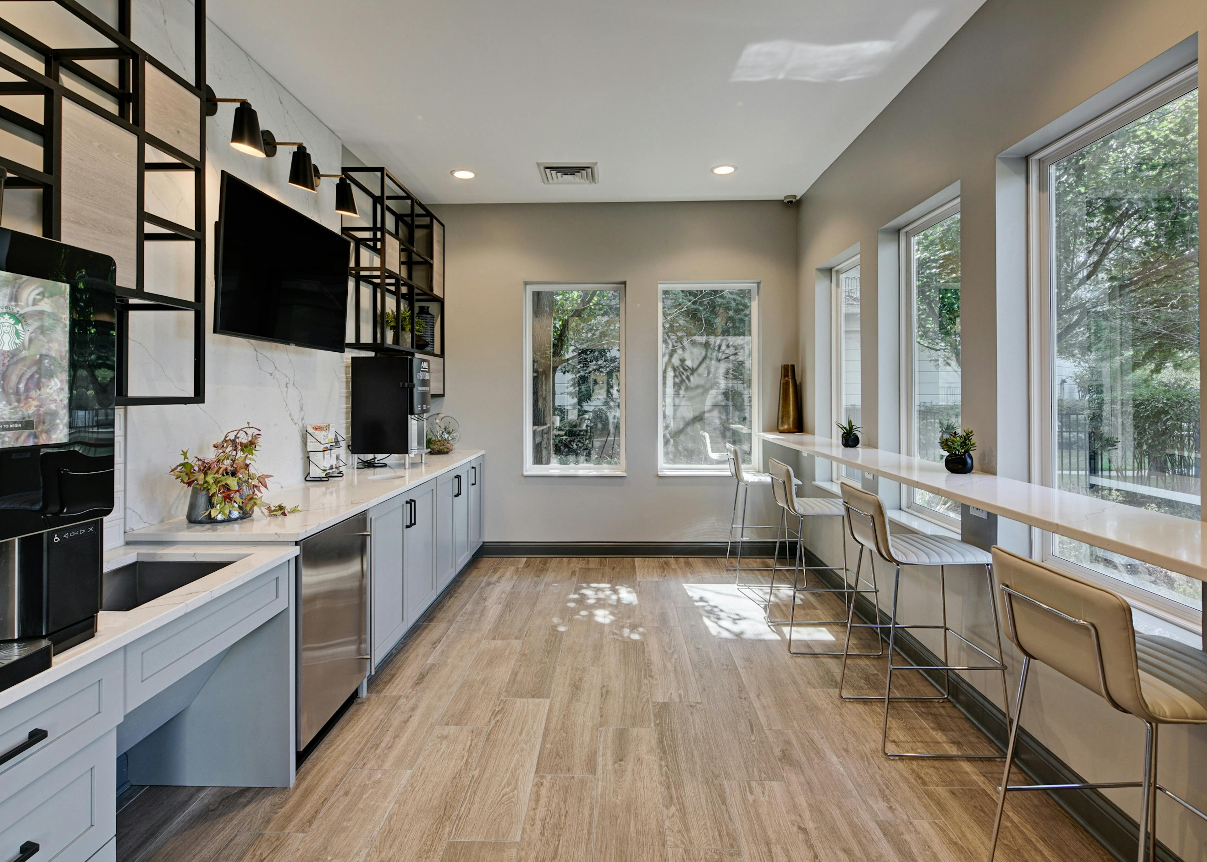 Coffee bar and kitchen area at AMLI at Seven Bridges with Starbucks coffee machine and wall of windows with counter and stools
