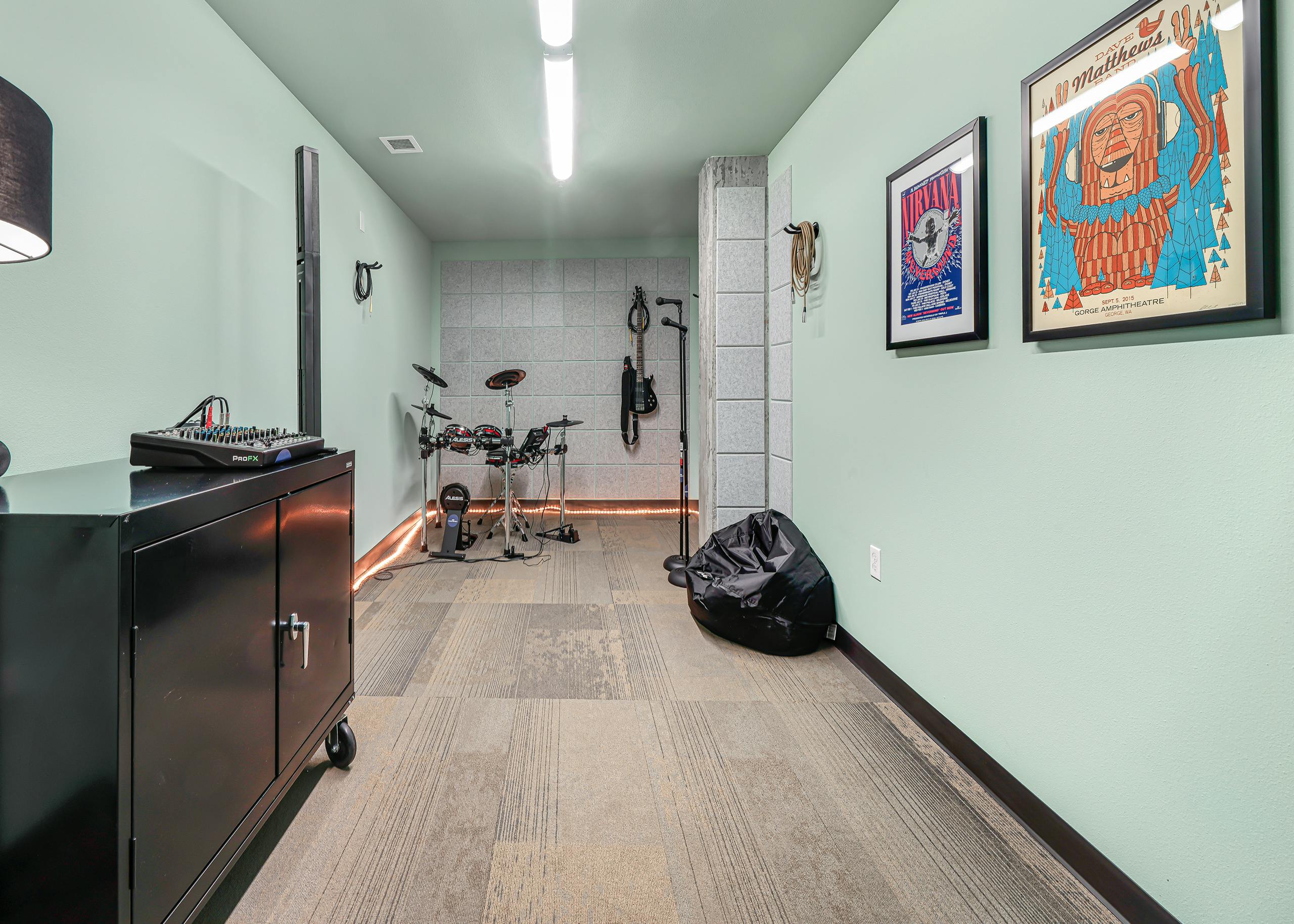 AMLI Spring District music room with pale green walls and electronic drum set and microphones and hanging electric guitar