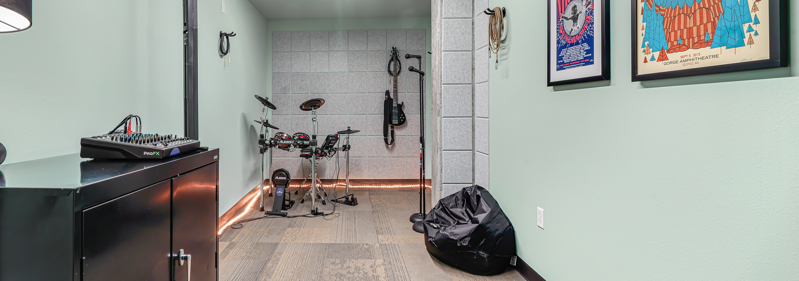 AMLI Spring District music room with pale green walls and electronic drum set and microphones and hanging electric guitar