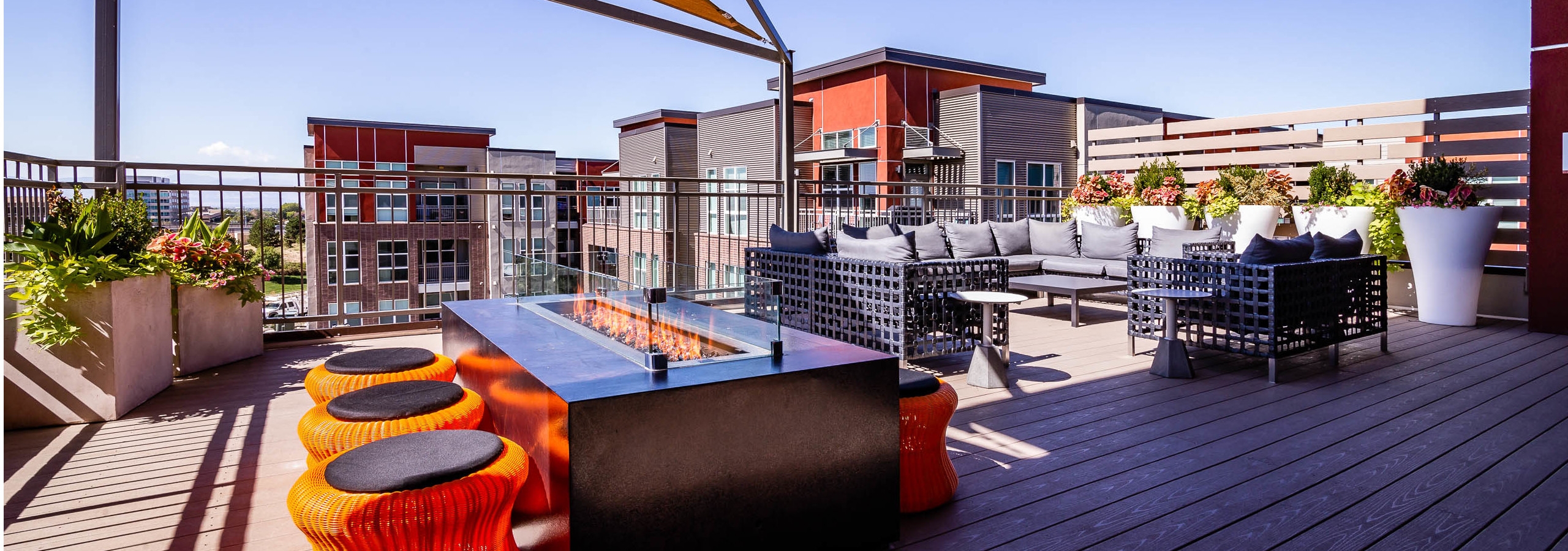View of the rooftop at AMLI Dry Creek apartments with a fire pit and surrounding short stools as well as a sectional couch