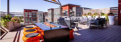 View of the rooftop at AMLI Dry Creek apartments with a fire pit and surrounding short stools as well as a sectional couch