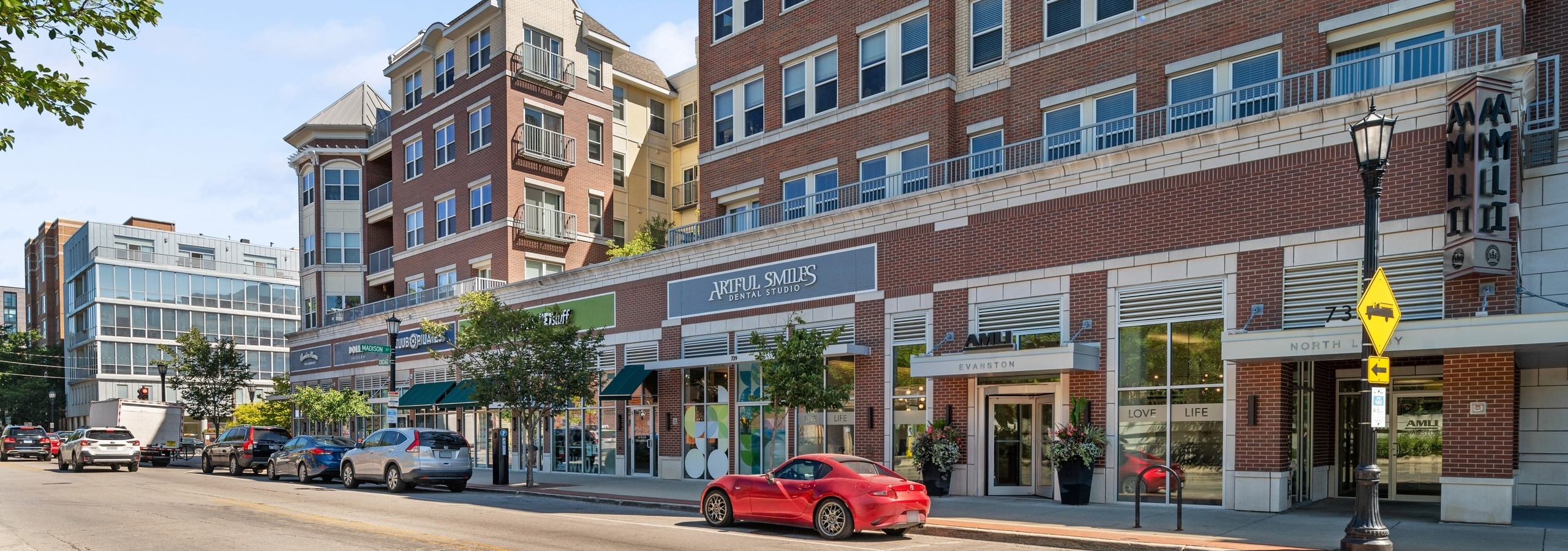 Exterior view of leasing office entrance and retail stores at AMLI Evanston apartment building with red brick façade