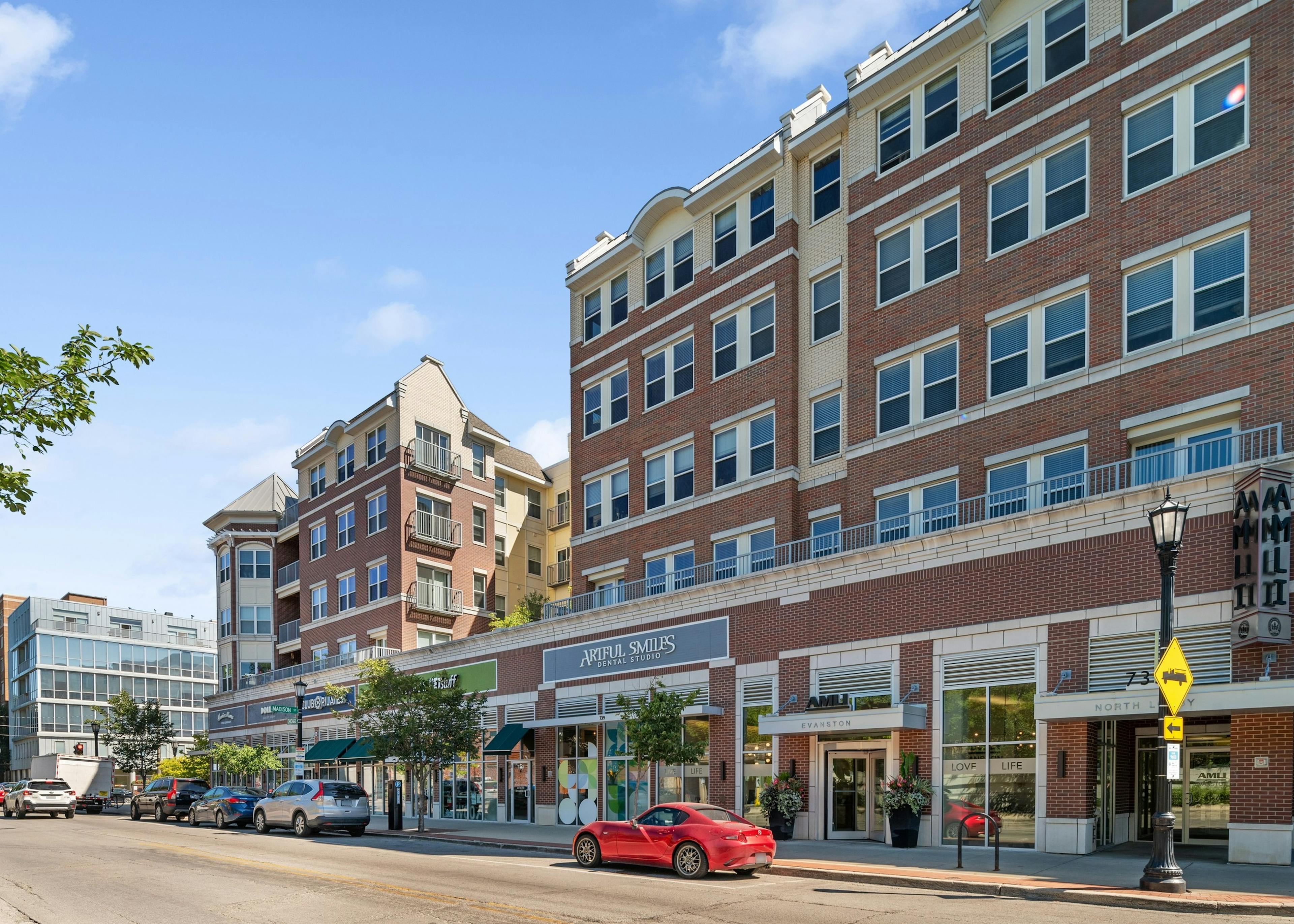 Exterior view of leasing office entrance and retail stores at AMLI Evanston apartment building with red brick façade
