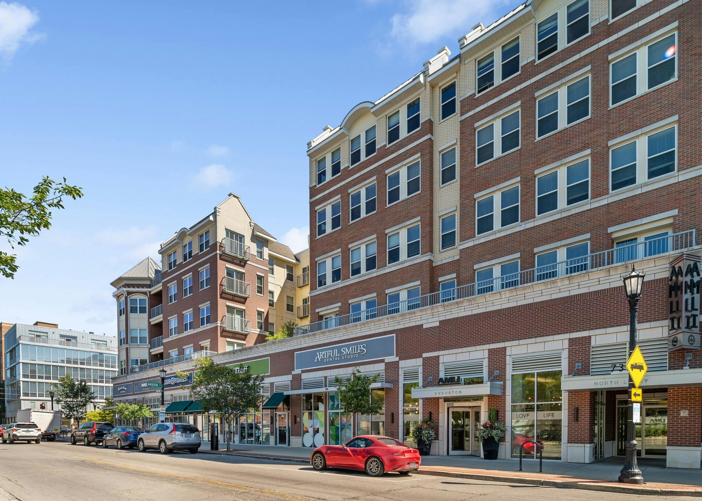 Exterior view of leasing office entrance and retail stores at AMLI Evanston apartment building with red brick façade