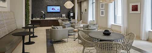 AMLI River North morning room with different tables and chairs throughout and tan walls with multiple windows bringing light