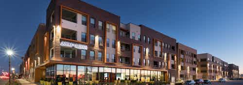 Exterior view of AMLI on Aldrich building facade at nighttime with a bright lamppost and reflecting window lights