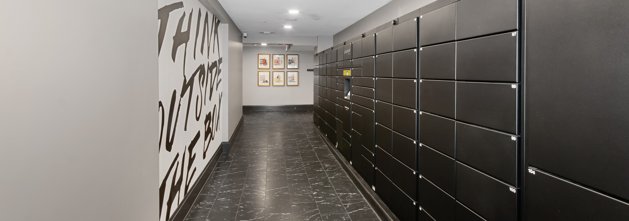 Resident package room at AMLI Quadrangle apartments featuring a white statement wall with black lettering and package lockers