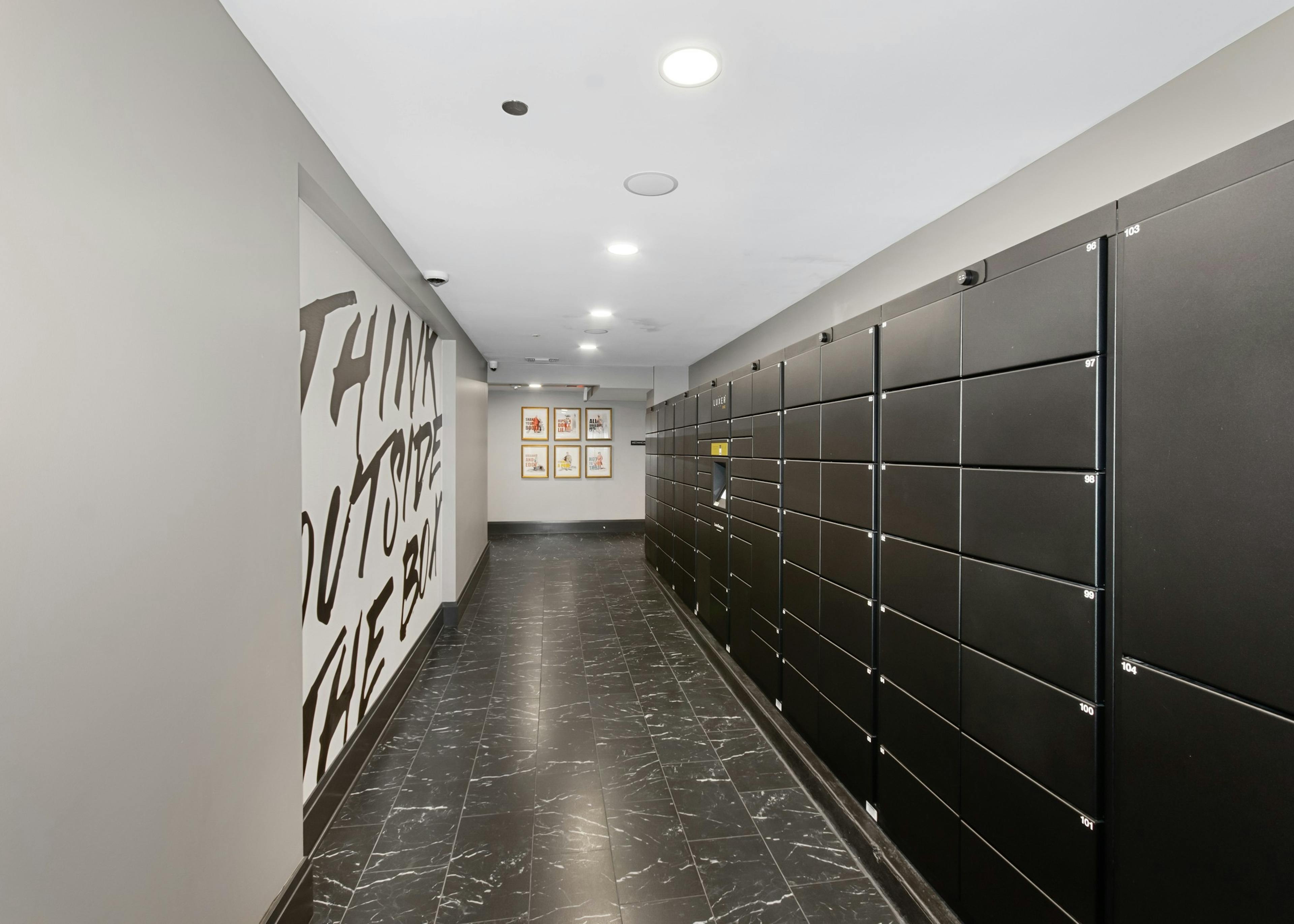 Resident package room at AMLI Quadrangle apartments featuring a white statement wall with black lettering and package lockers