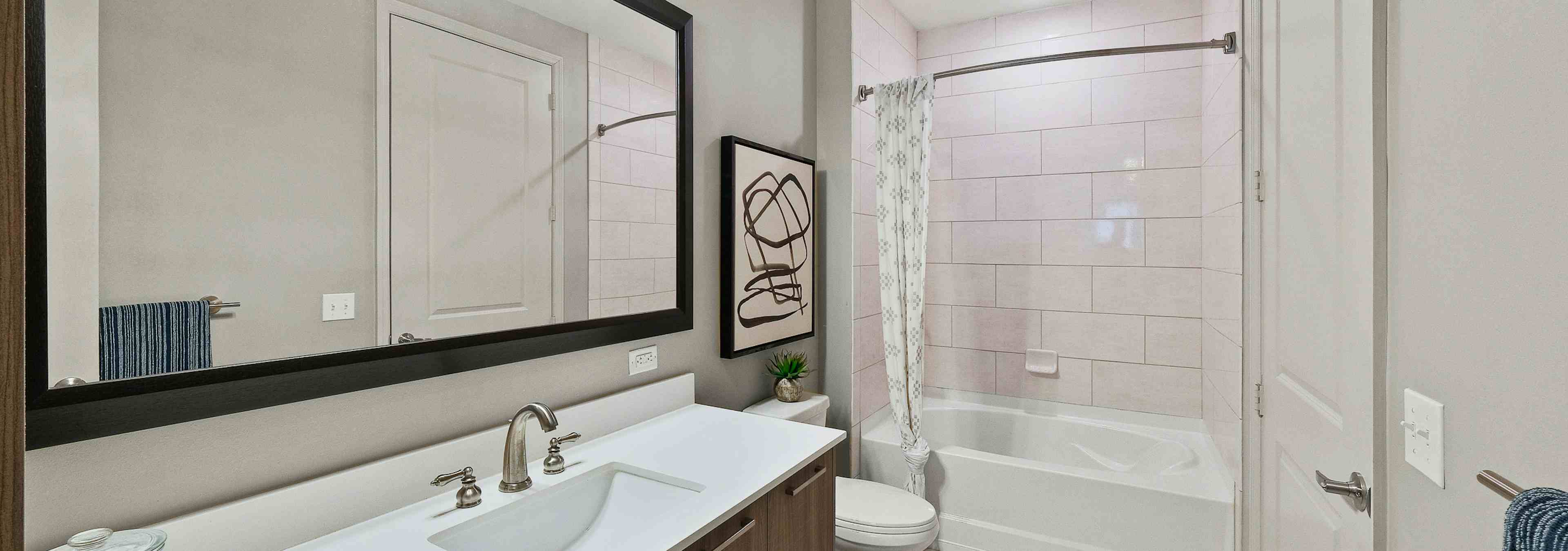  Interior view of AMLI 8800 apartment bathroom with large single vanity, sink with faucet, mirror, toilet and soaking tub