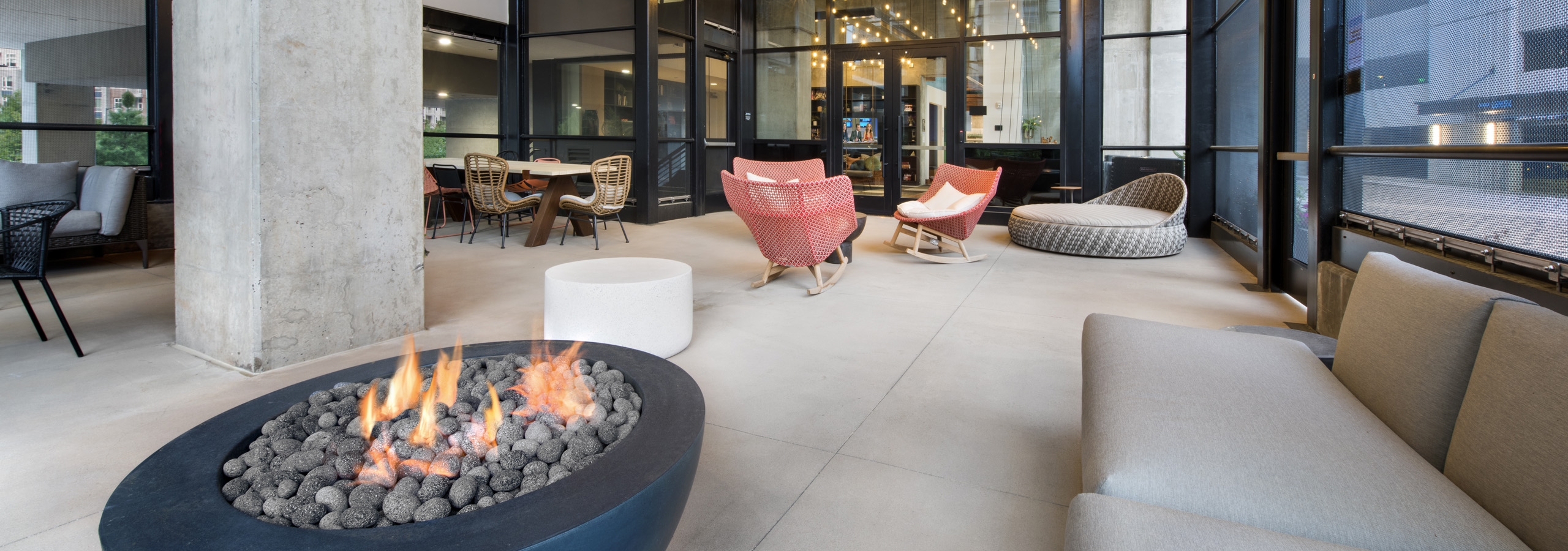 Interior view of AMLI Lenox screened in common space with fire pit and multiple seating areas with brightly colored chairs