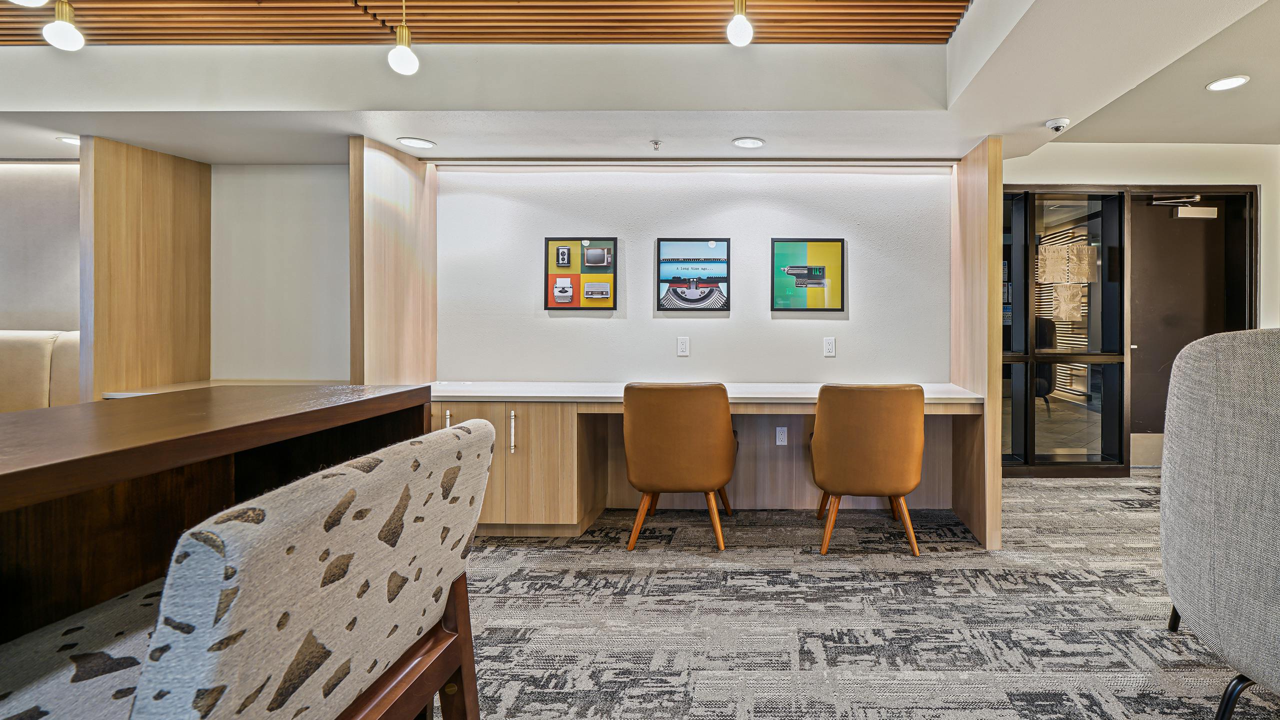 Interior view of AMLI Bellevue Park business center with gray carpet and 2 brown chairs at desk and wood slat ceiling