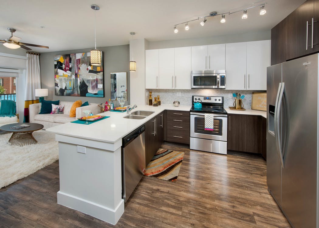 Interior of AMLI Piedmont Heights kitchen with stainless steel appliances and white granite countertops with dark hardwood