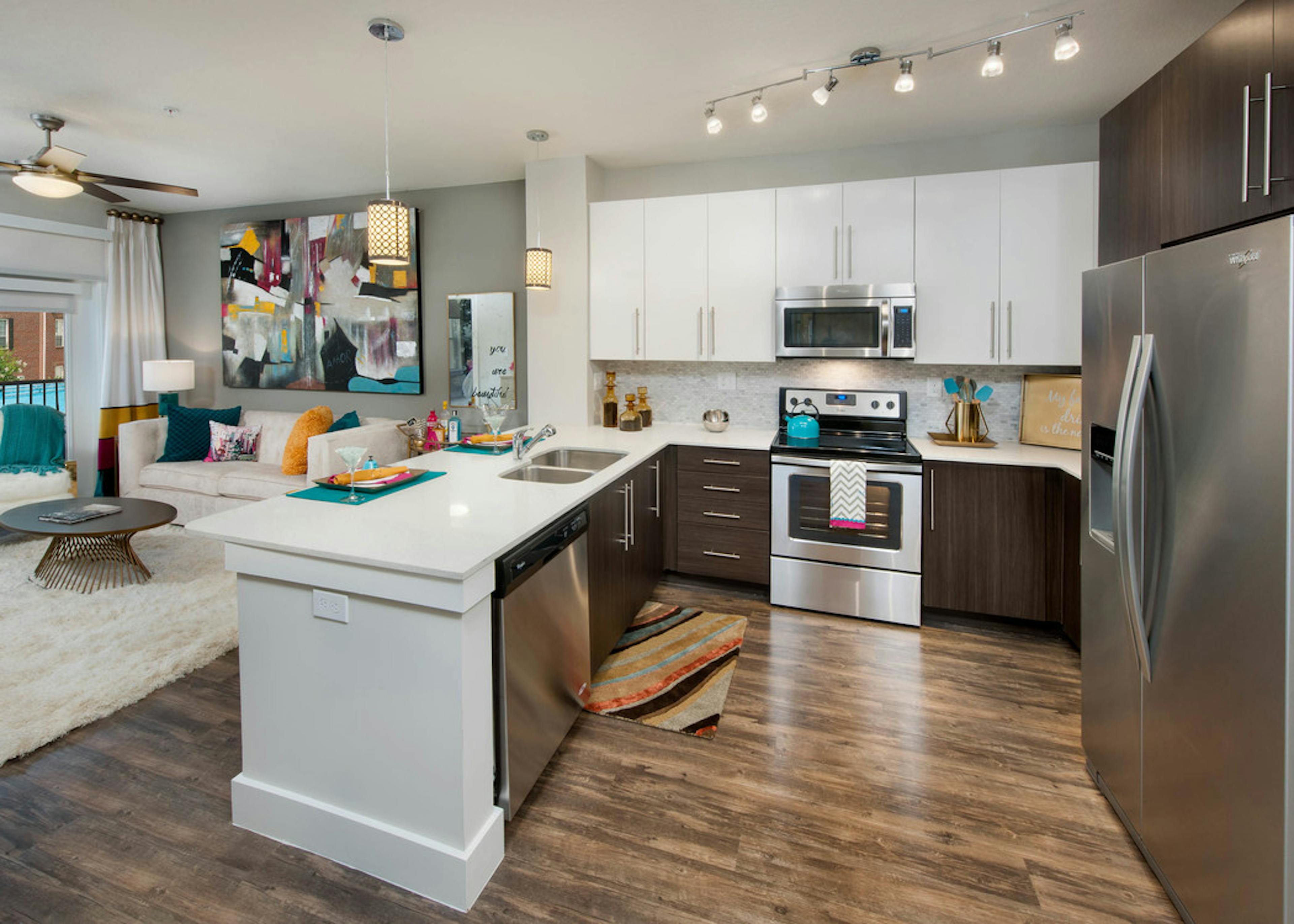 Interior of AMLI Piedmont Heights kitchen with stainless steel appliances and white granite countertops with dark hardwood