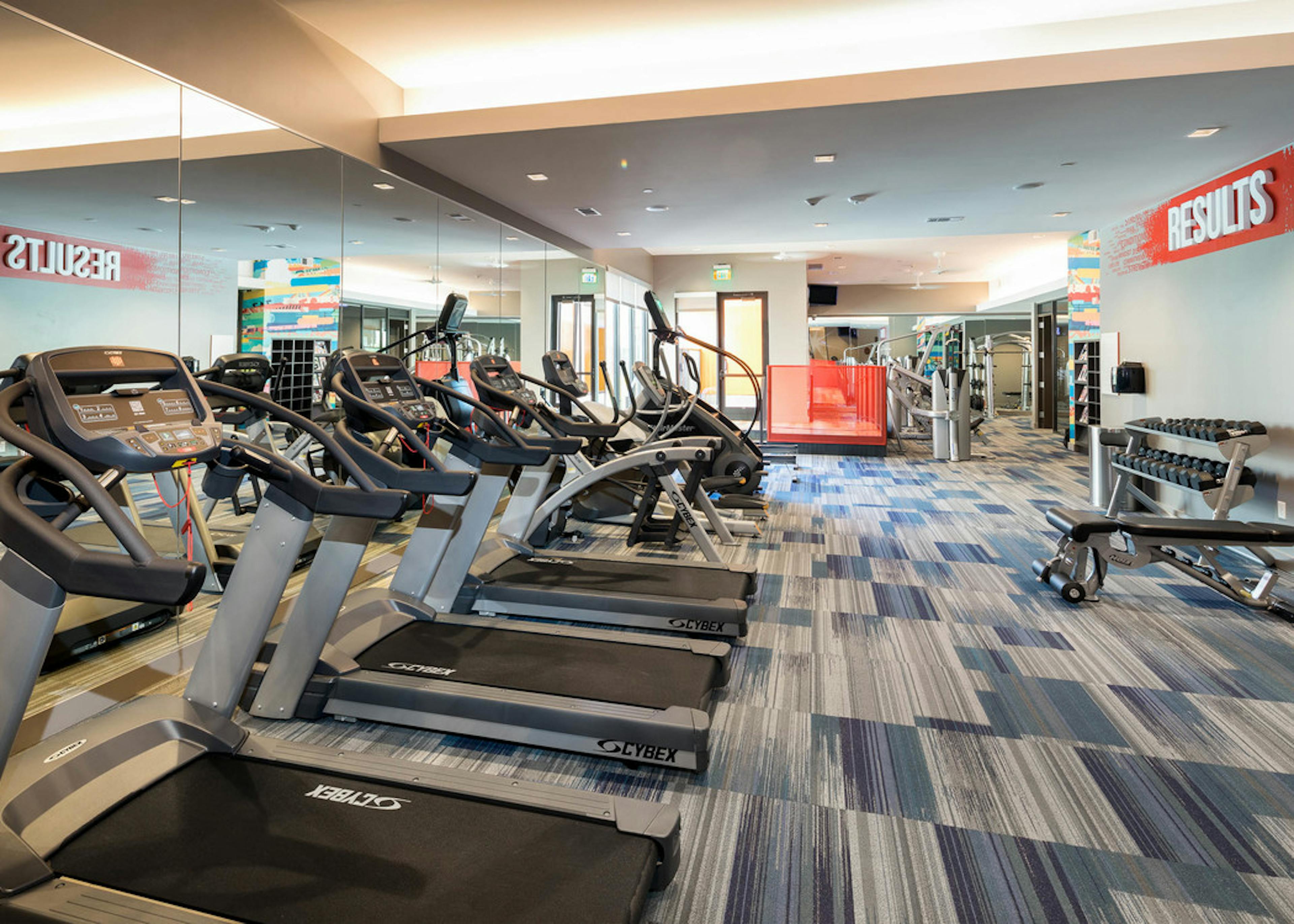 Interior close up of exercise machines in the fitness center at AMLI on Aldrich with blue and grey flooring and light walls