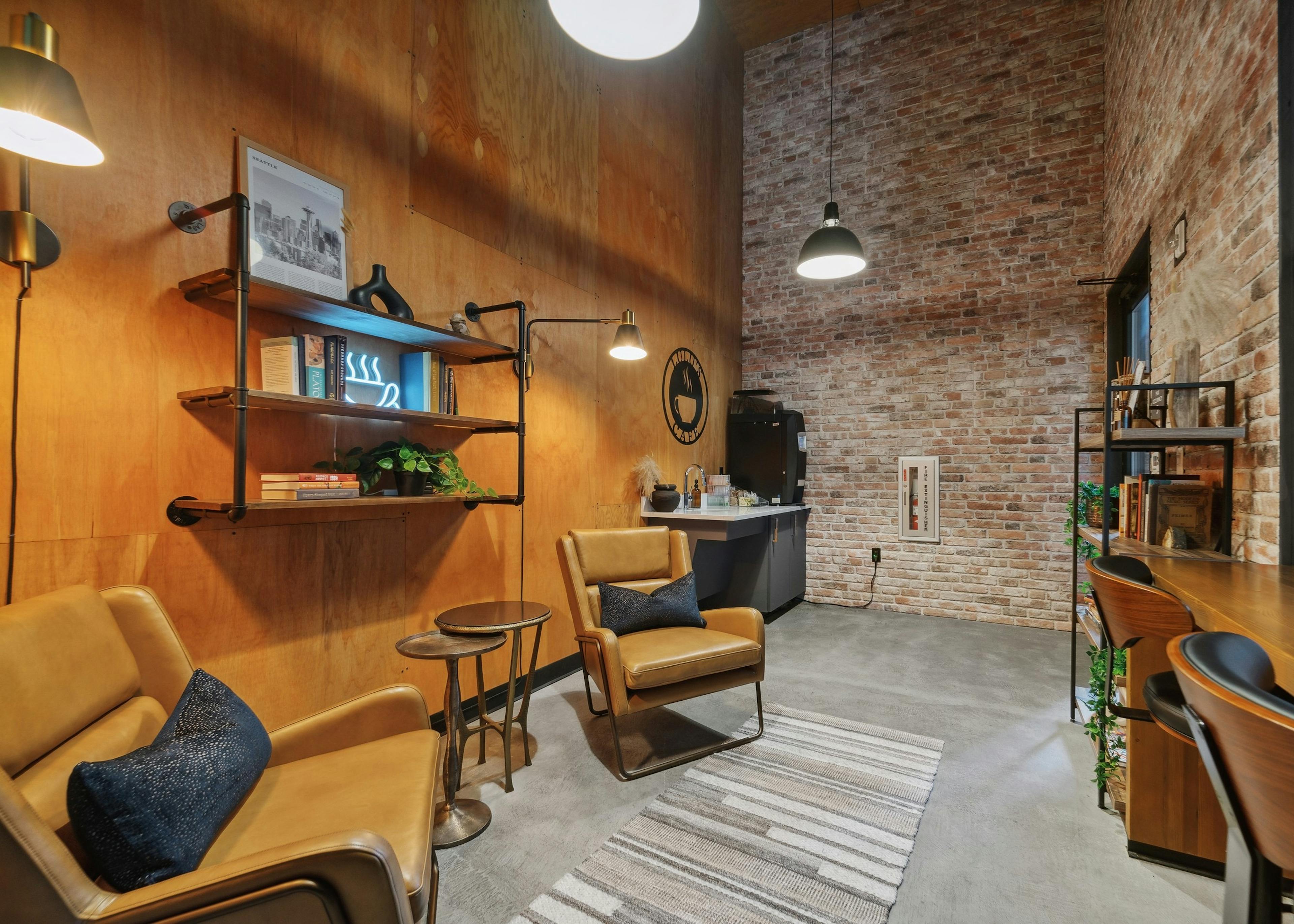 Café at AMLI South Lake Union with a coffee station and leather chairs and bookshelves on a wood wall and 2 brick walls