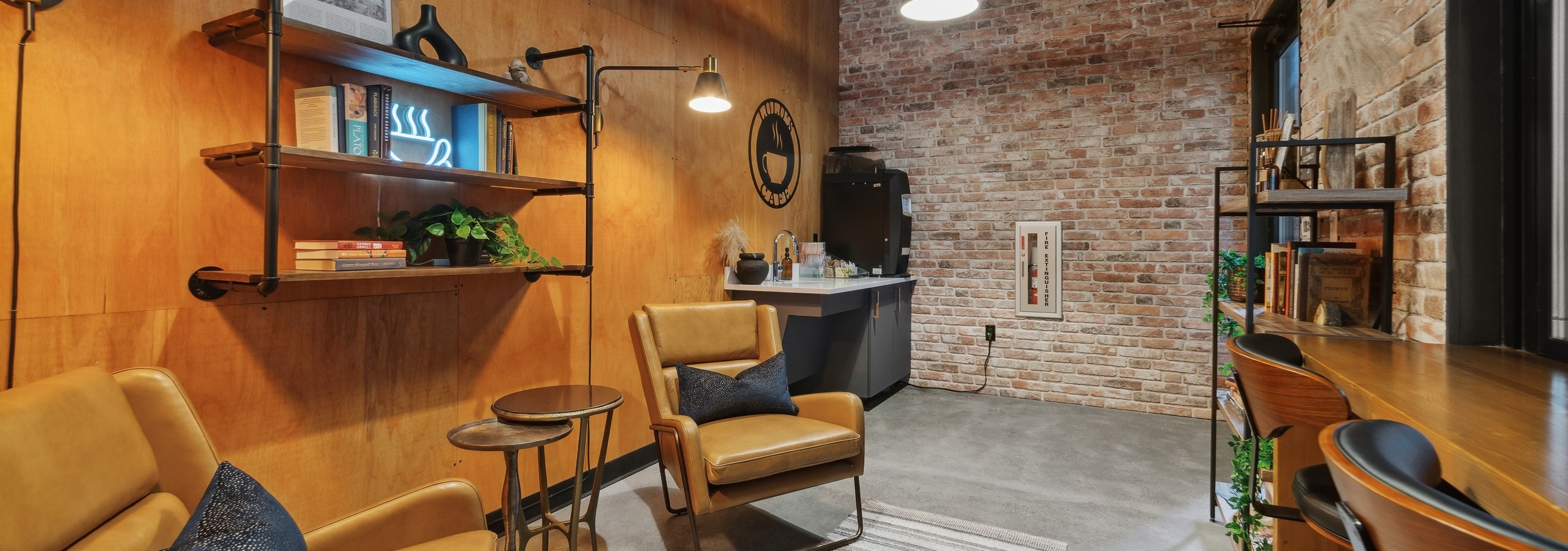 Café at AMLI South Lake Union with a coffee station and leather chairs and bookshelves on a wood wall and 2 brick walls