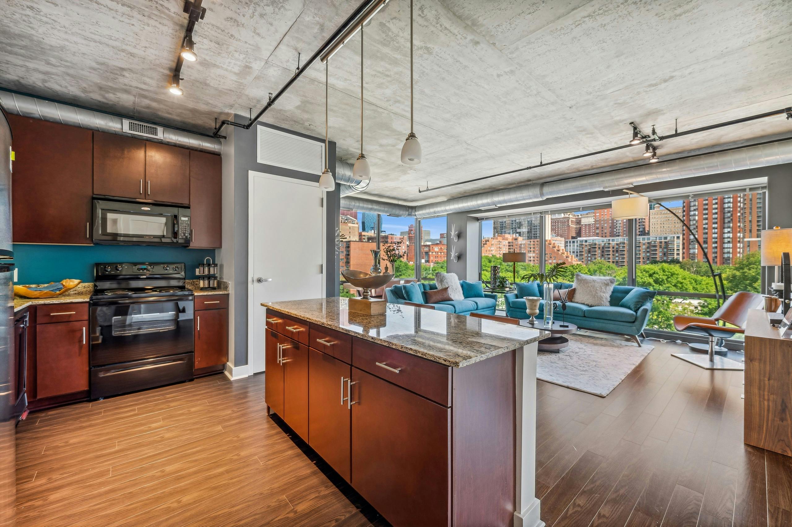 Kitchen with dark wood cabinets and granite countertops and living area with wall of windows at AMLI 900 apartments