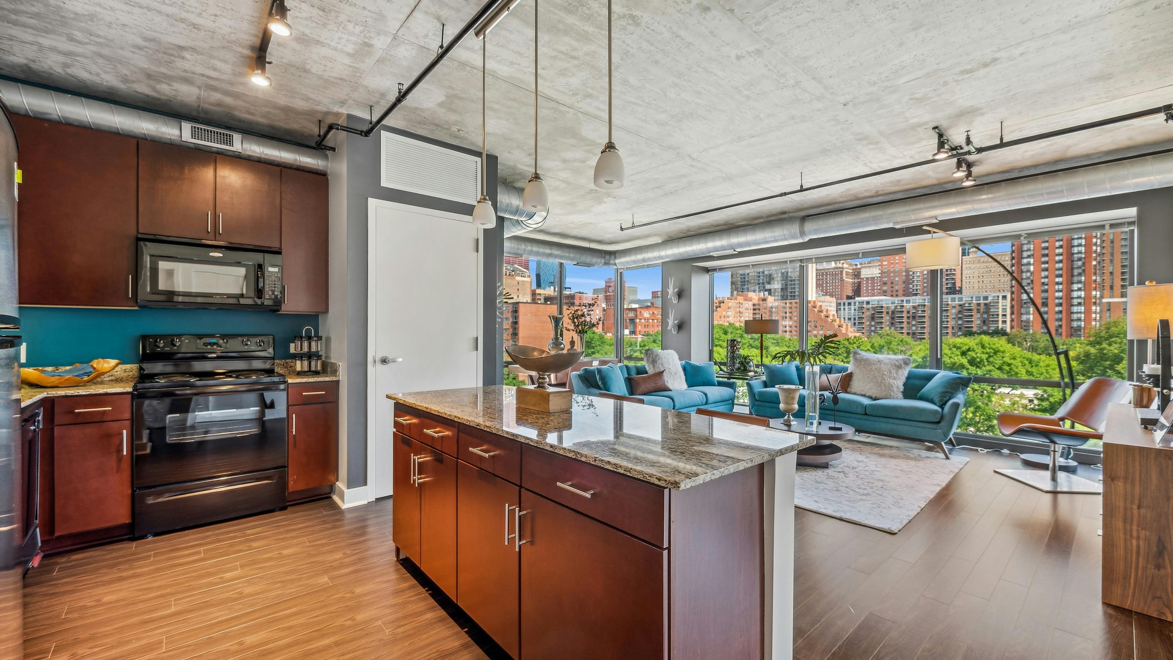 Kitchen with dark wood cabinets and granite countertops and living area with wall of windows  at AMLI 900 apartments