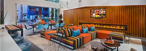 Interior of clubhouse with comfortable seating options and shuffle board and big screen TV at AMLI Uptown Orange apartments